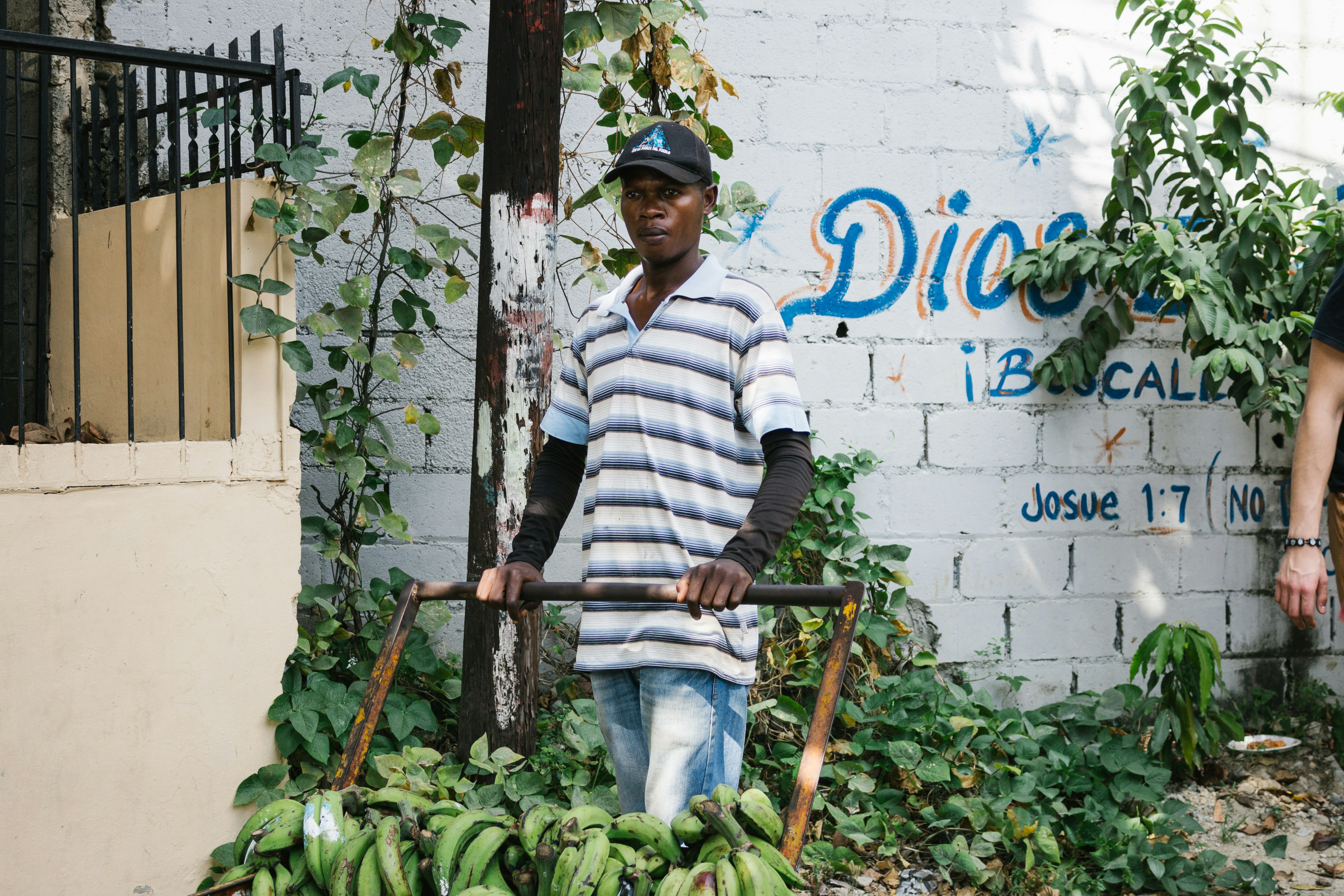 A man pushes a cart of bananas on the street.