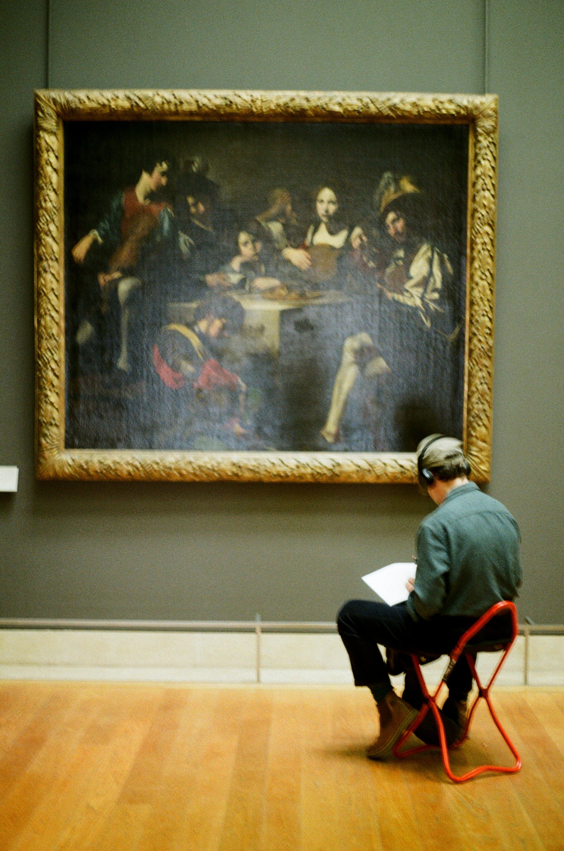 Person sits in front of a painting in a museum.