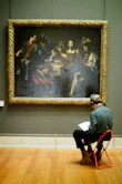 Person sits in front of a painting in a museum.