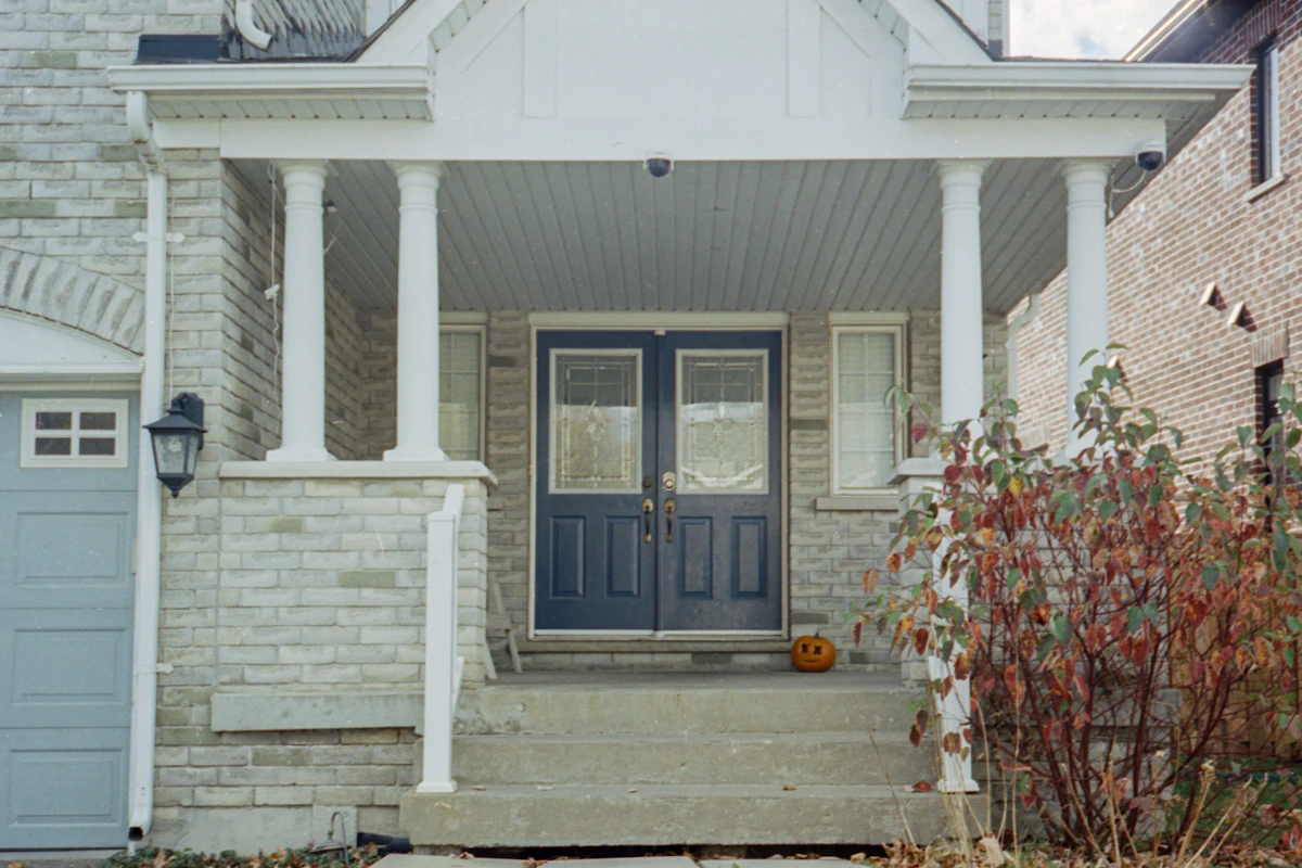 A stone-faced house with a covered front porch, white columns and a navy double door