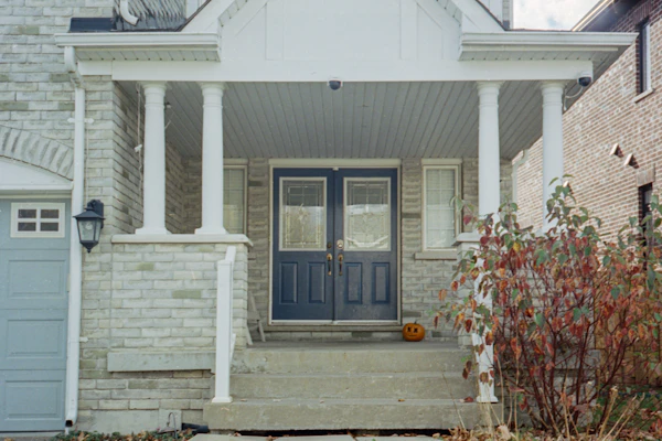 A stone-faced house with a covered front porch, white columns and a navy double door