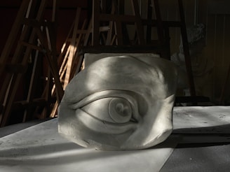 A sculpted eye rests in a workshop.
