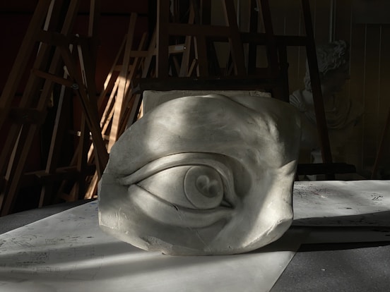 A sculpted eye rests in a workshop.