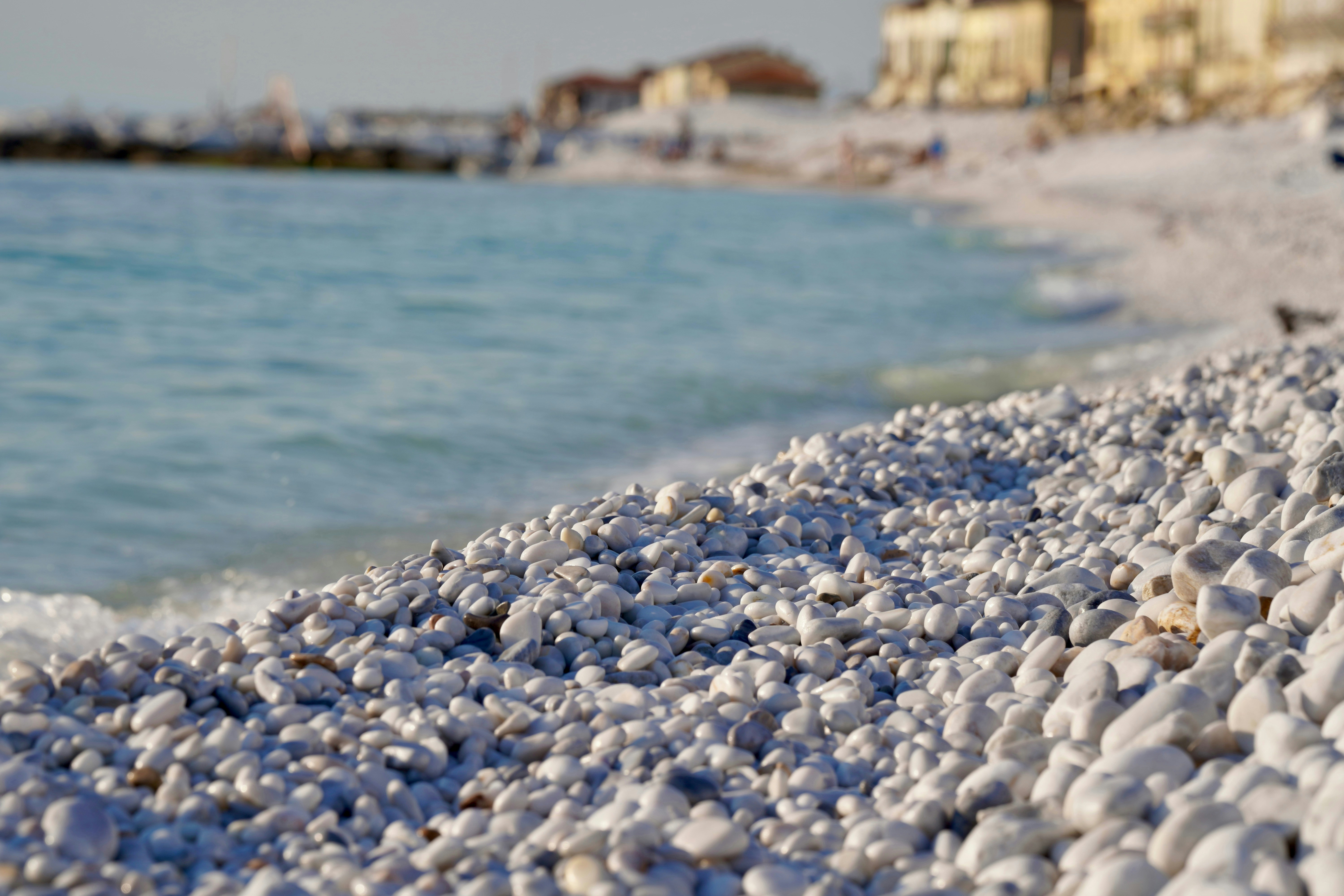 Pebbly beach with turquoise water in the background.