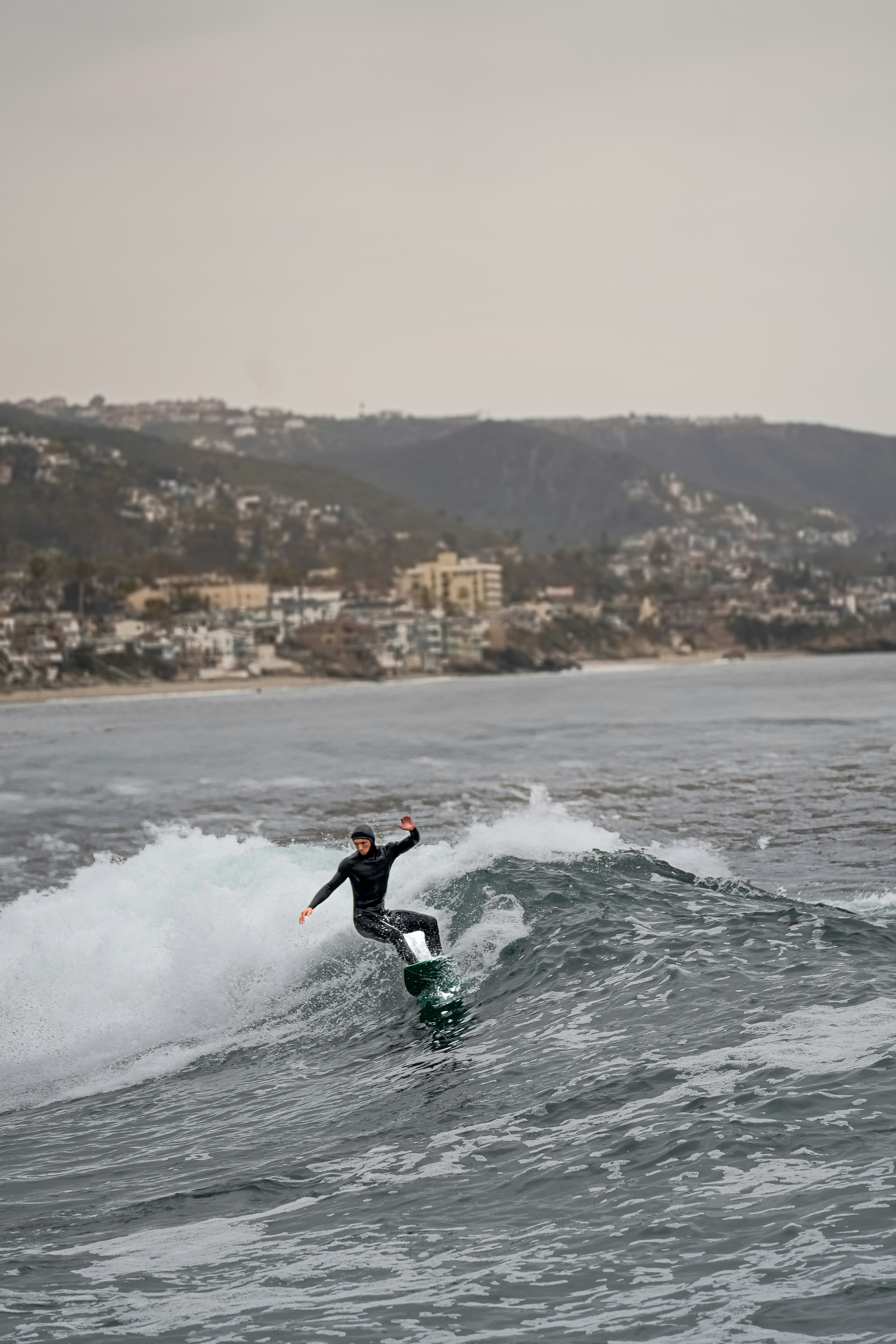 A surfer rides a wave near the coast.