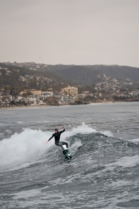 A surfer rides a wave near the coast.