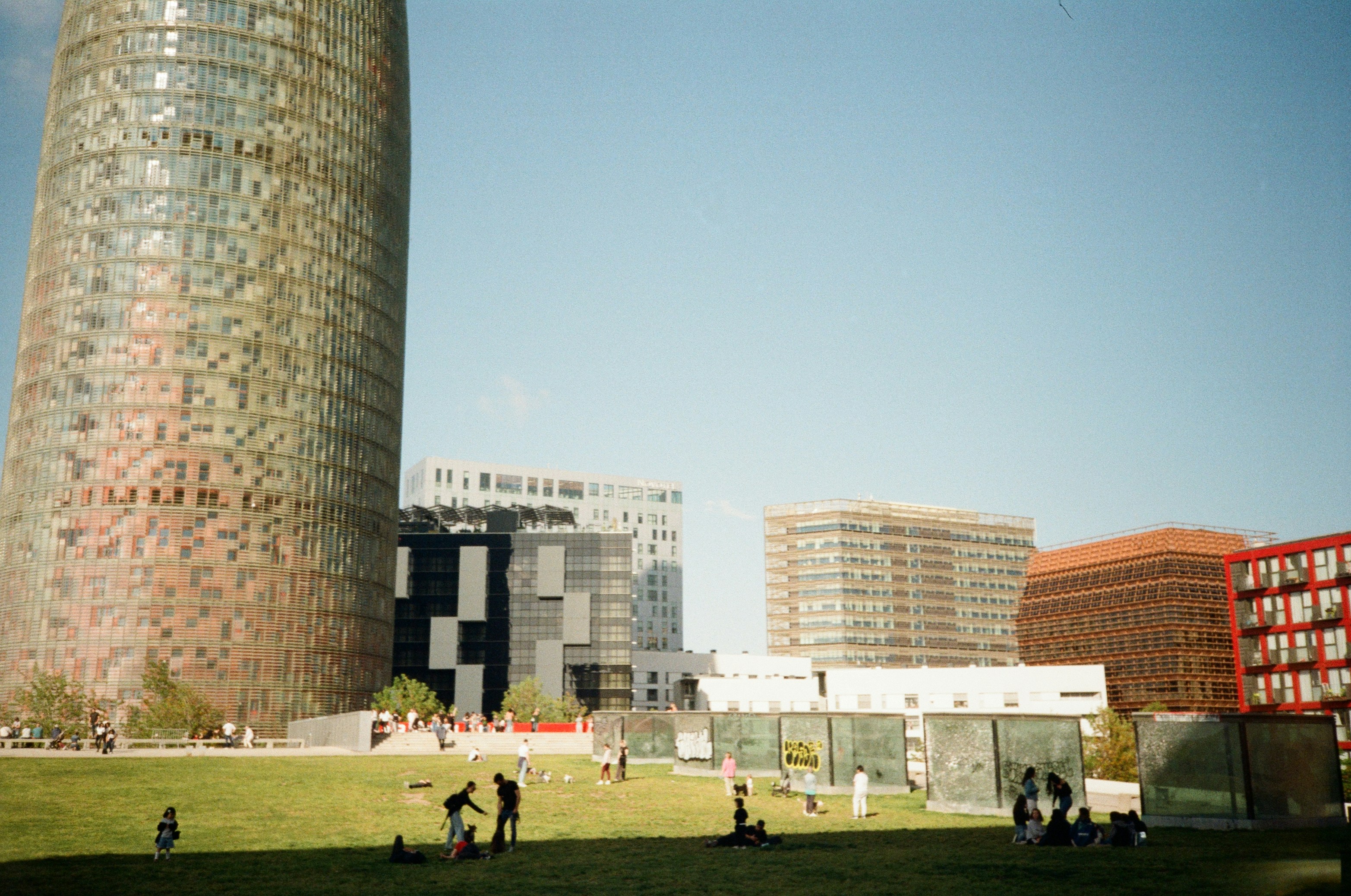 Modern buildings and green space under a blue sky.
