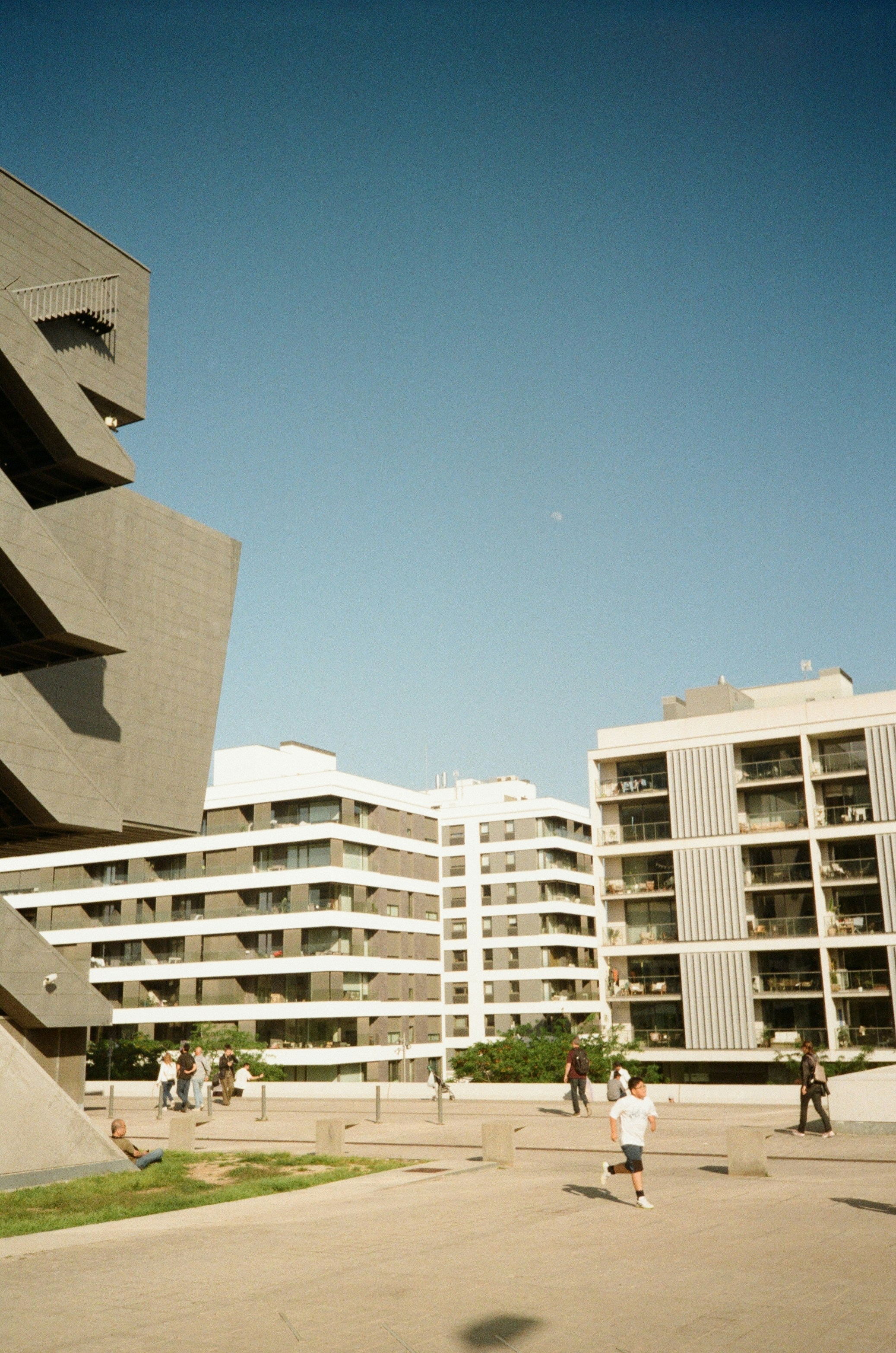 Modern buildings and a child running under a clear sky.