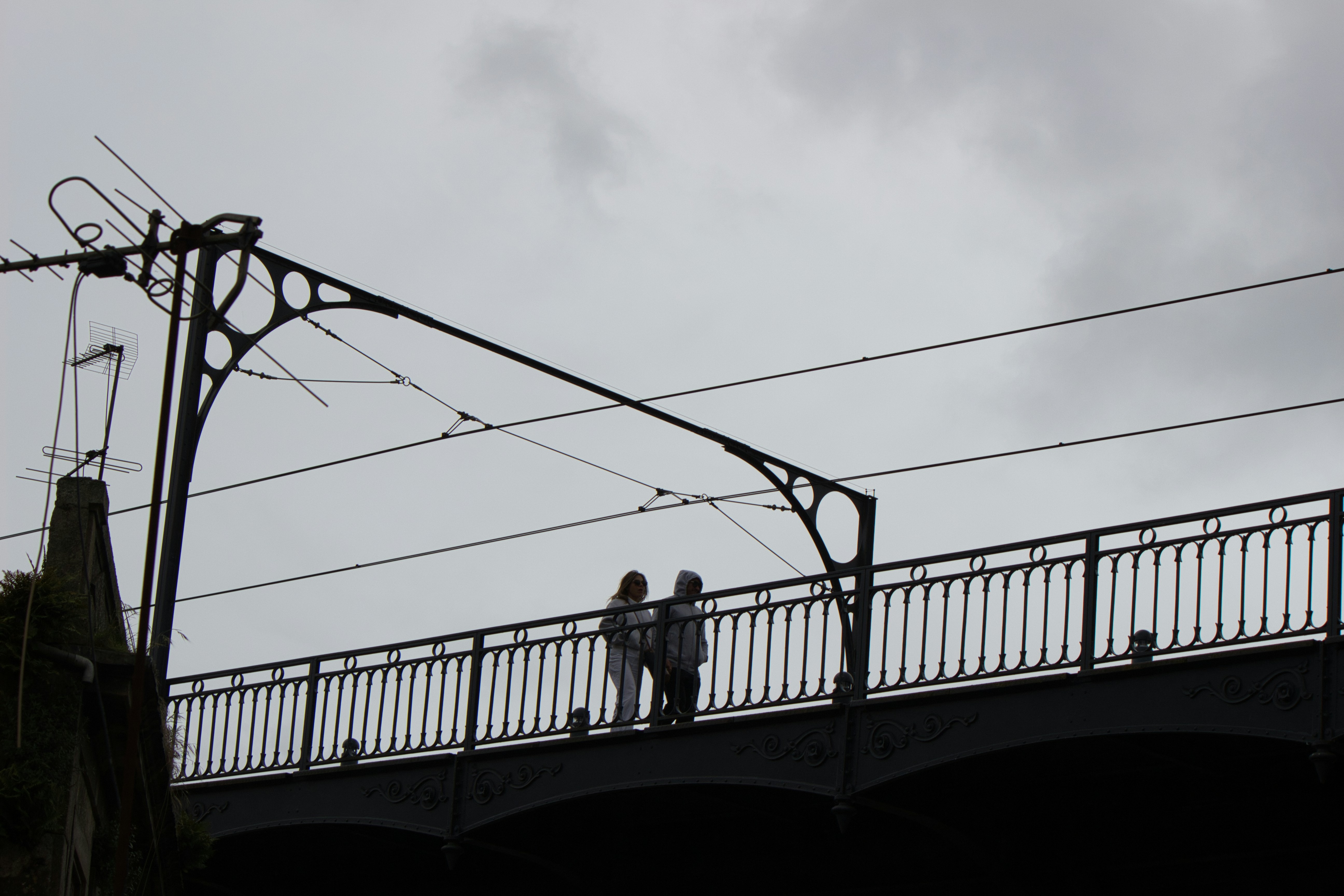Two people stand on a bridge.