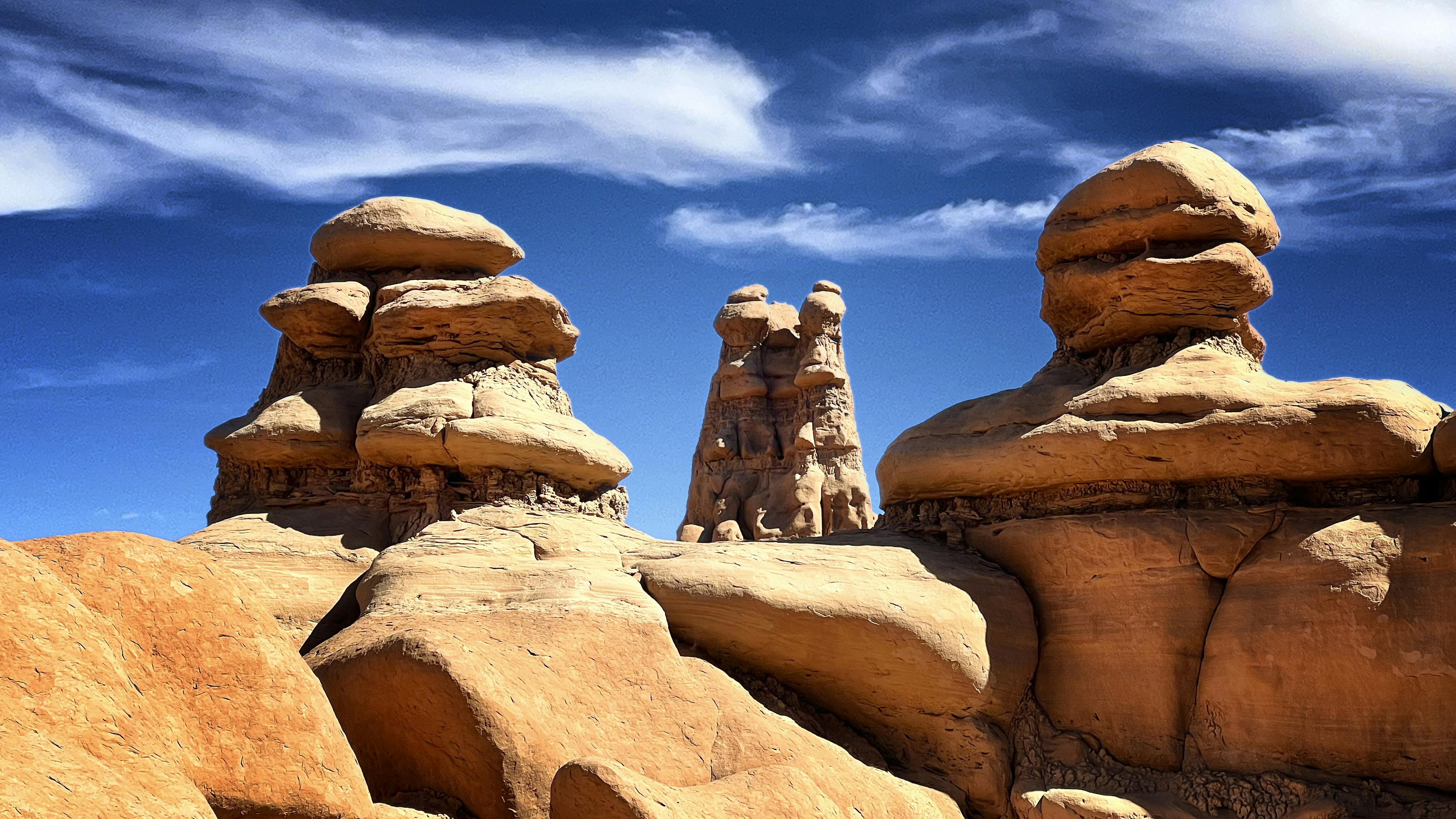 Unique rock formations stand under a bright blue sky.
