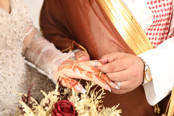 A groom places a ring on a bride's finger.