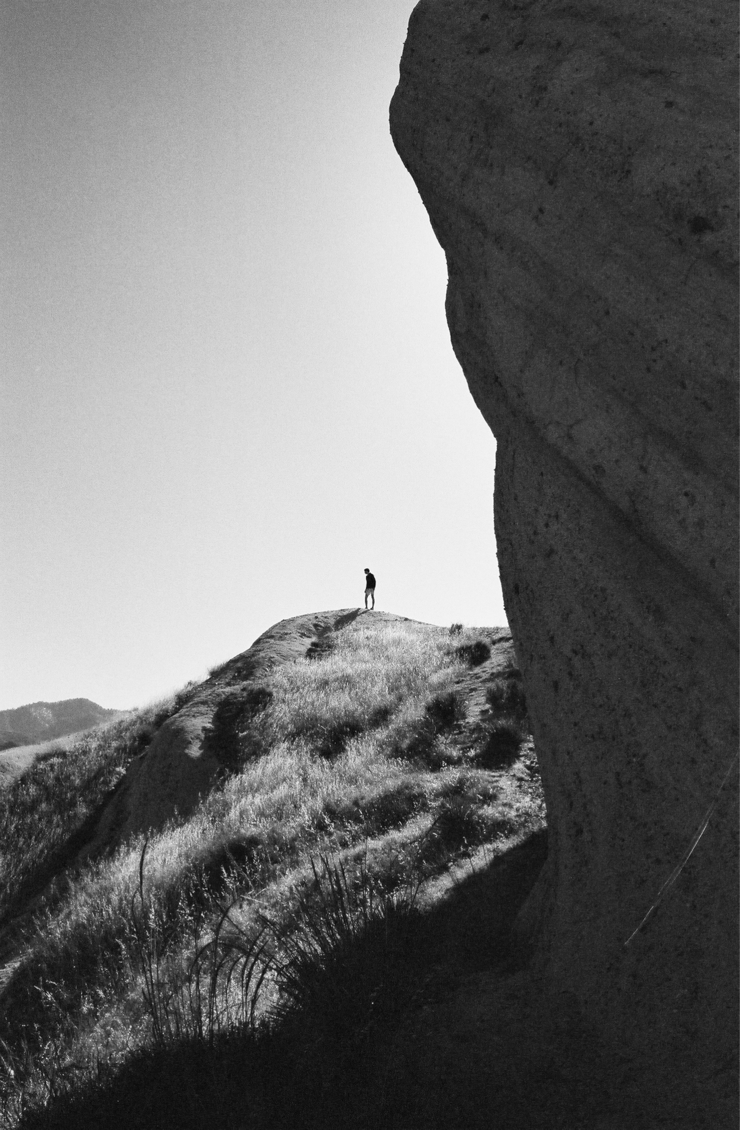 A person stands atop a grassy hill.