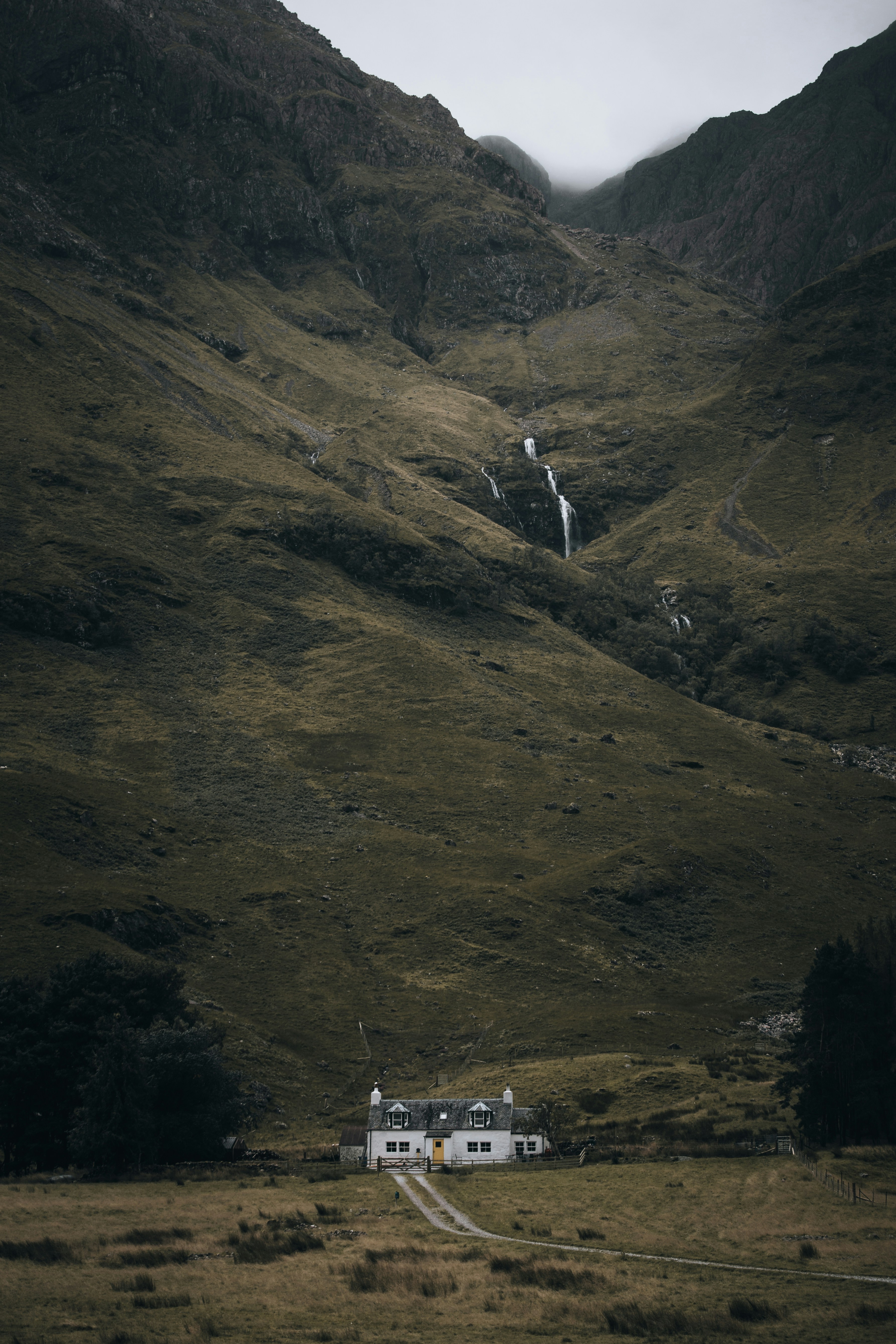 Une maison se trouve au milieu des montagnes et des cascades.