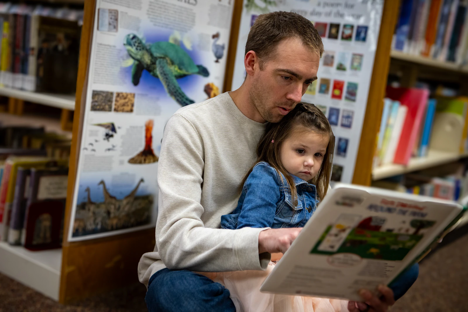 Ojciec czyta książkę córce w bibliotece dla dzieci