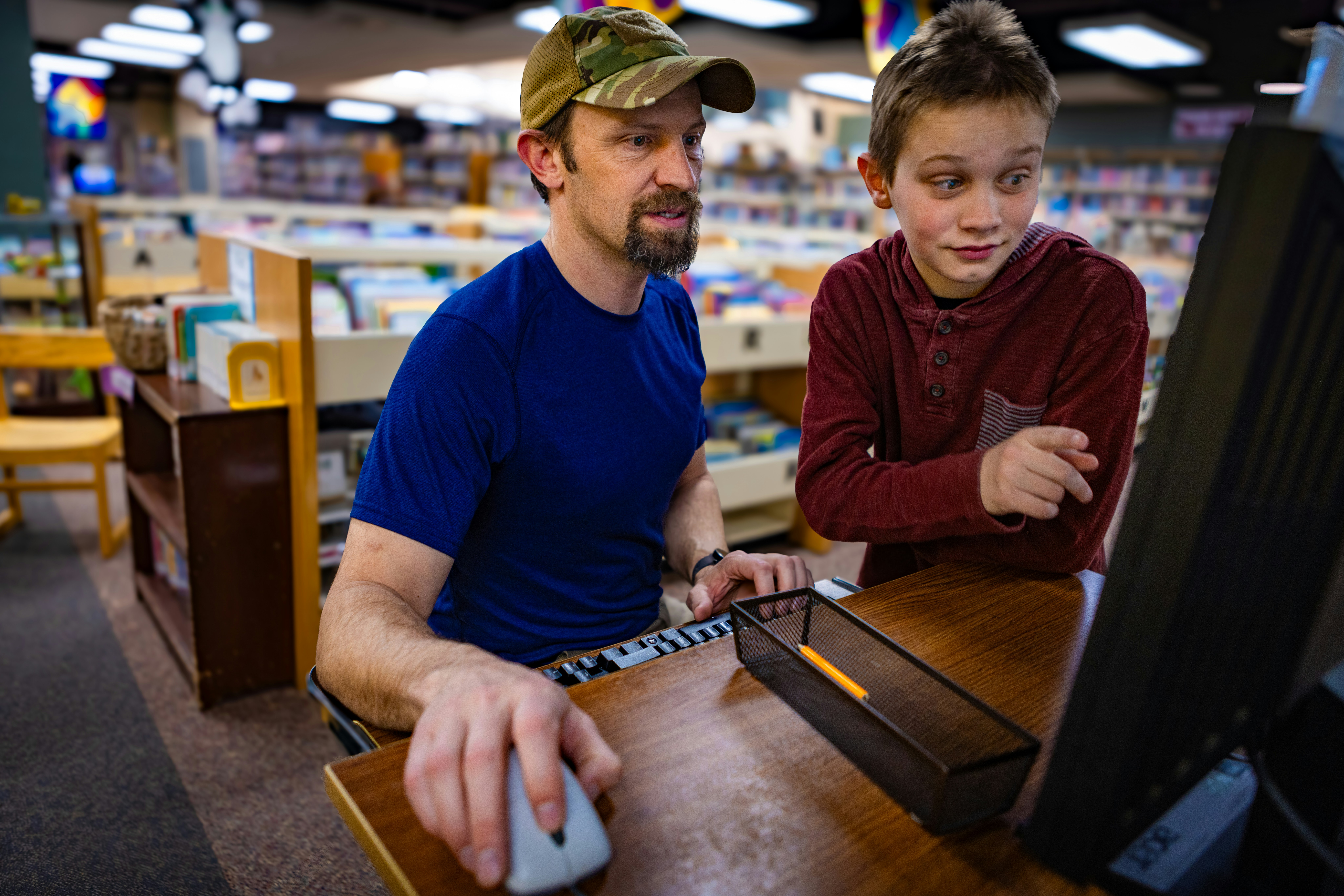 Luke and Simon Devoe look up a book on the online catalog on the internet on a computer at Marshall public library in Pocatello, Idaho on April 1, 2025.