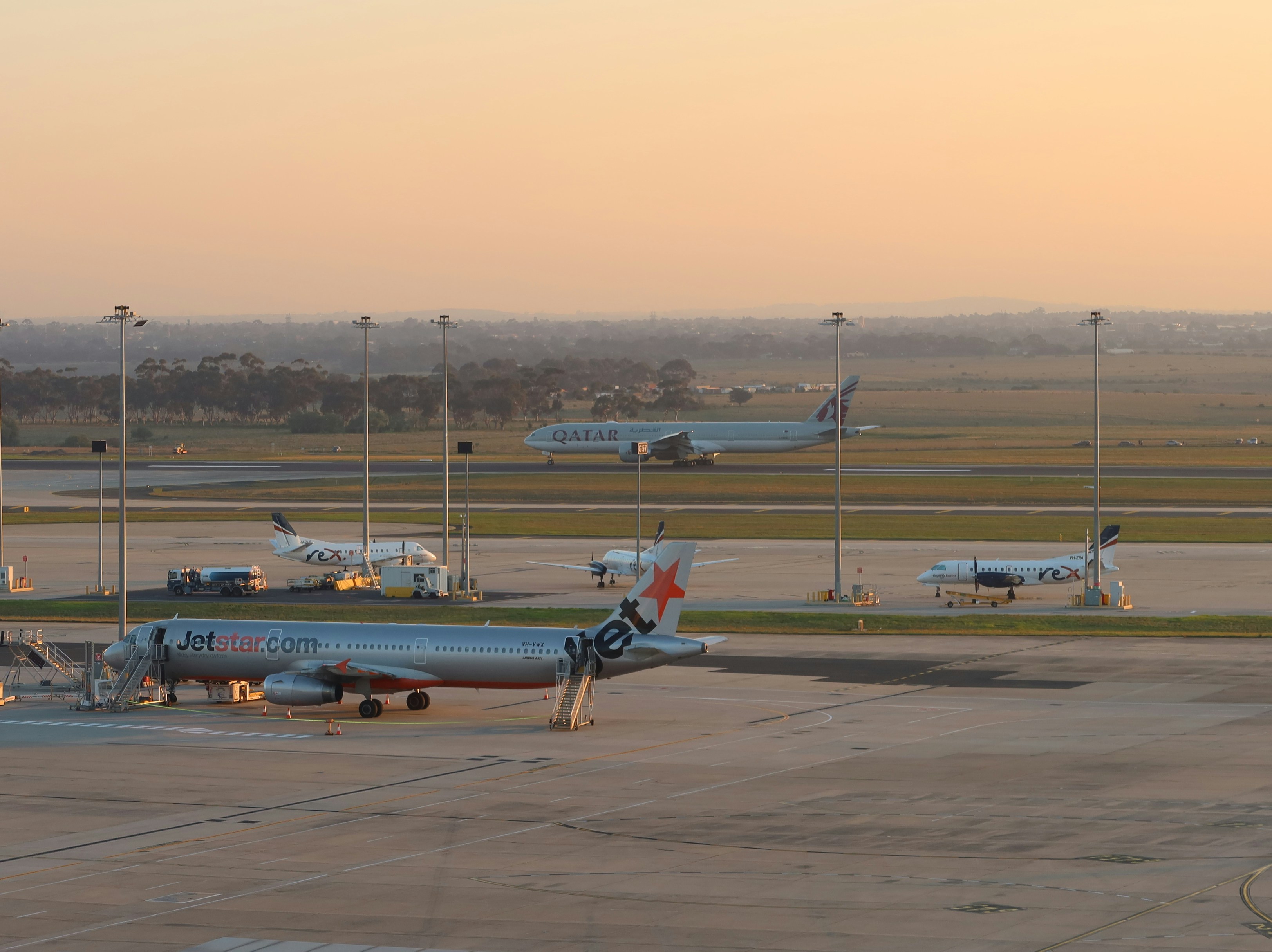 Airplanes are parked at an airport at sunset.