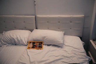 A bed is made with white pillows and sheets.