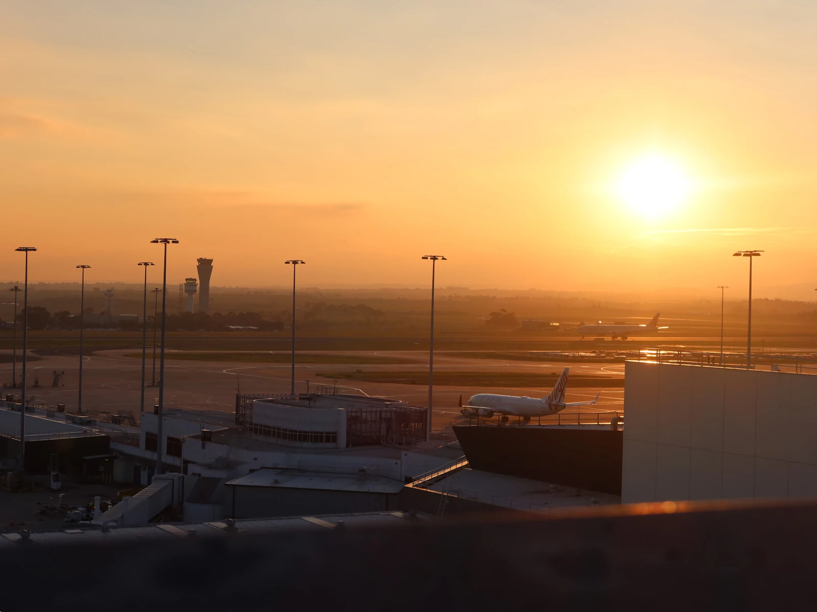 Sun setting over an airport apron with aircraft parked at the terminal