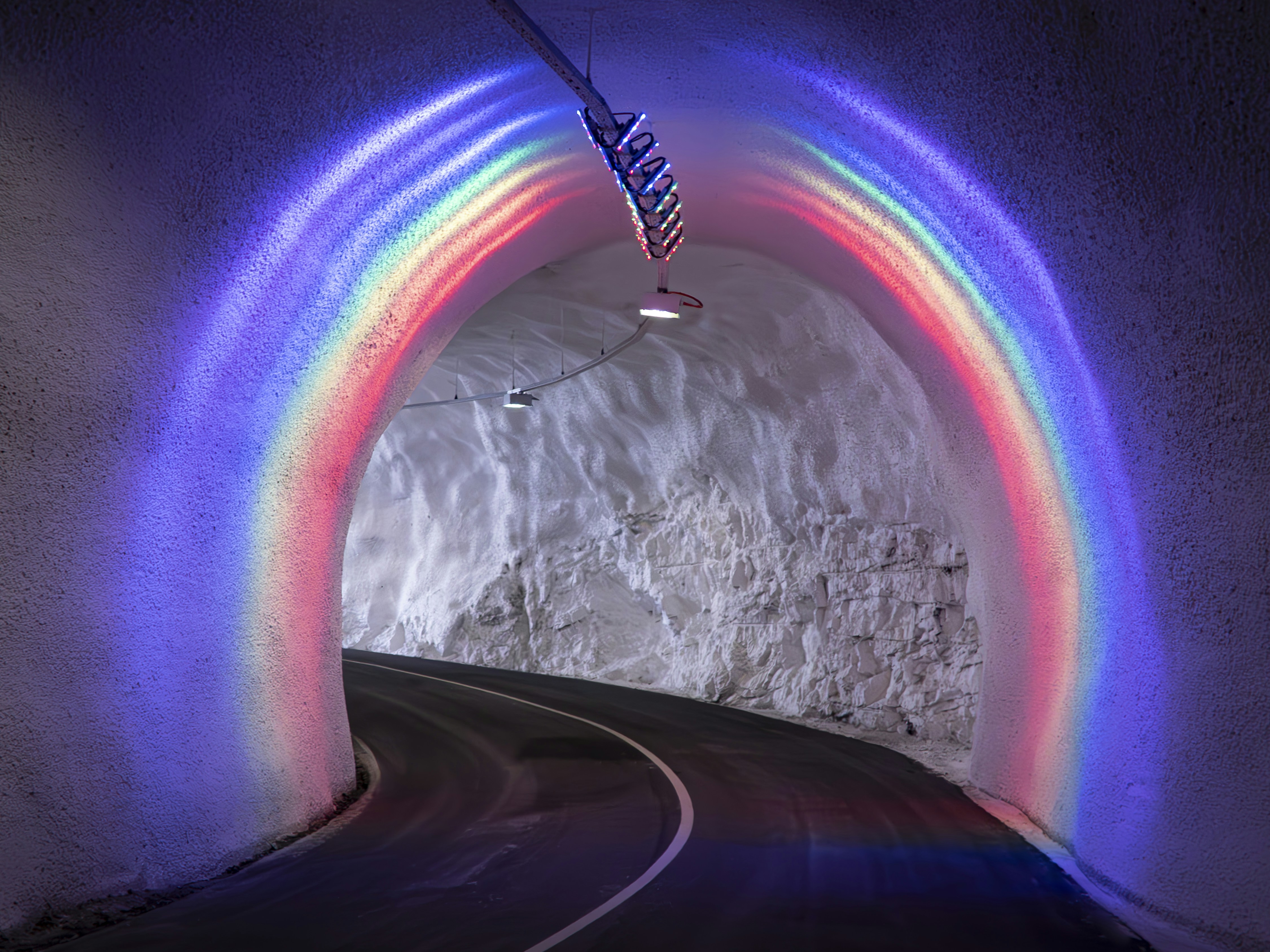 A tunnel entrance is lit with a colorful rainbow.