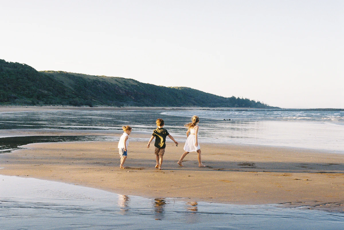 Three children are playing on a sandy beach.