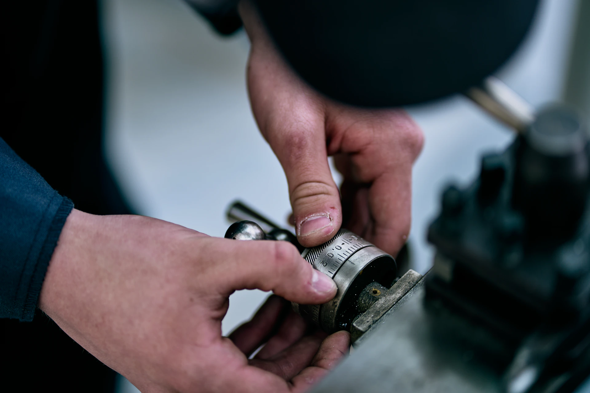 Hands manipulate a metal device on a table.