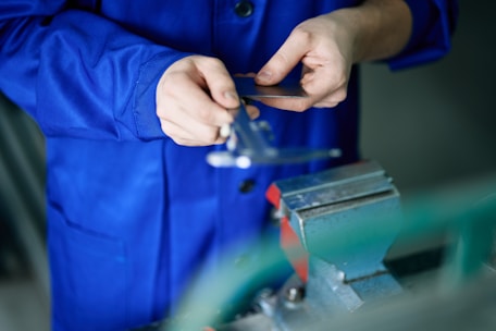 A worker uses calipers to measure a small object.