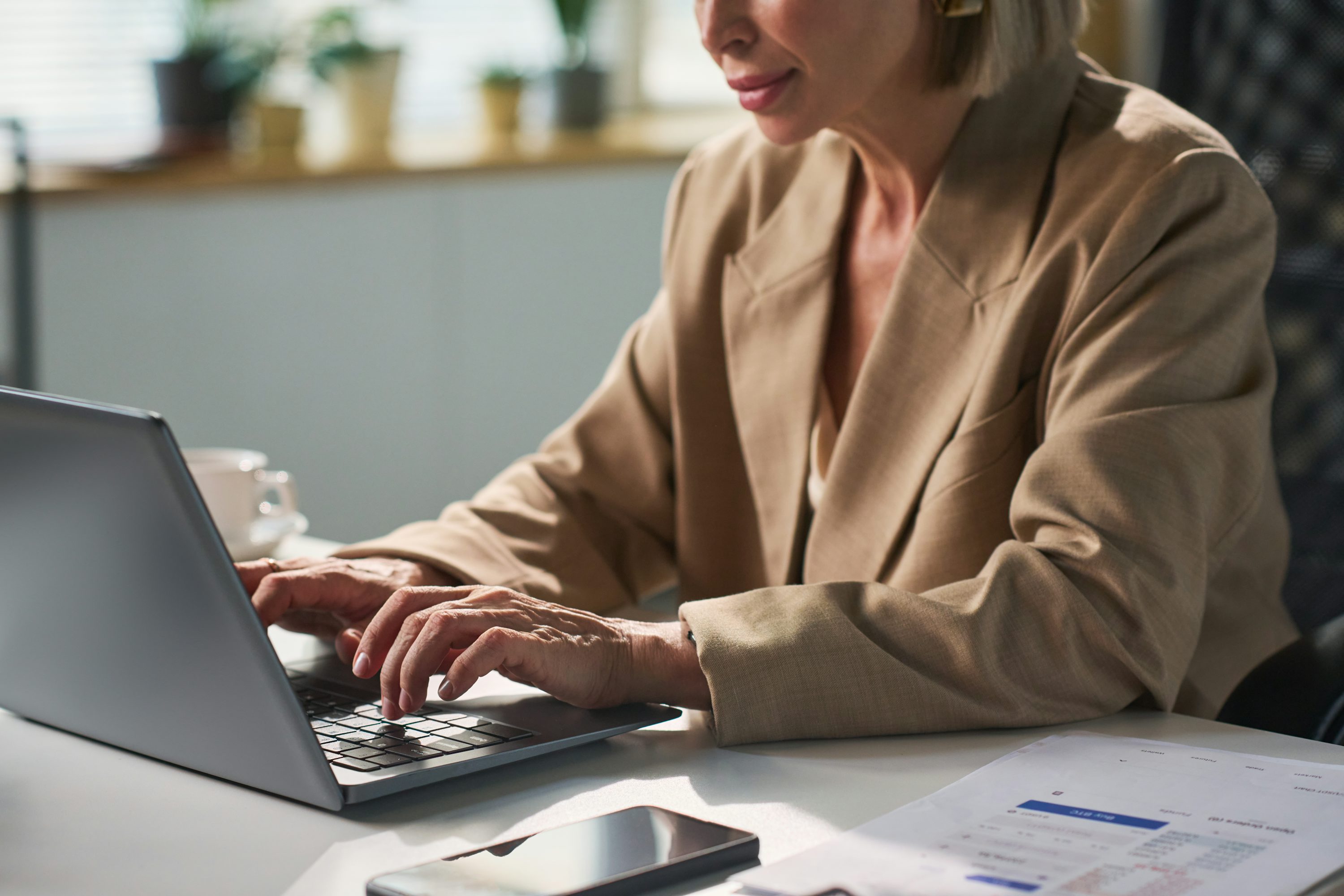 Woman types on laptop at a desk.