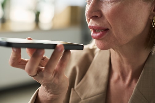 Woman is holding a phone to her mouth.