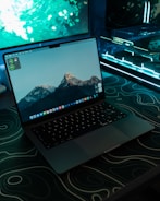A macbook sits open on a gaming setup.