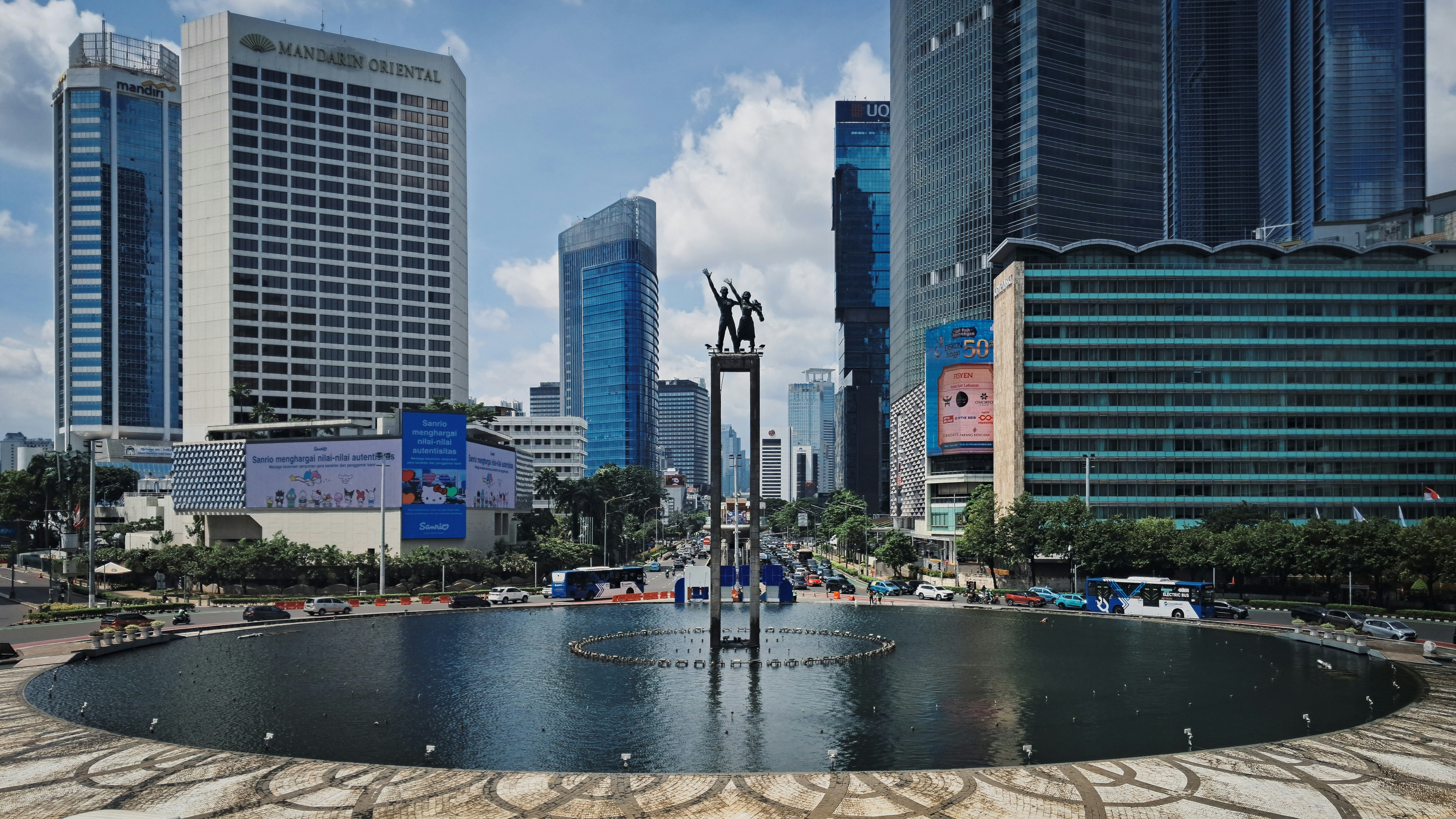A cityscape shows modern buildings around a statue.
