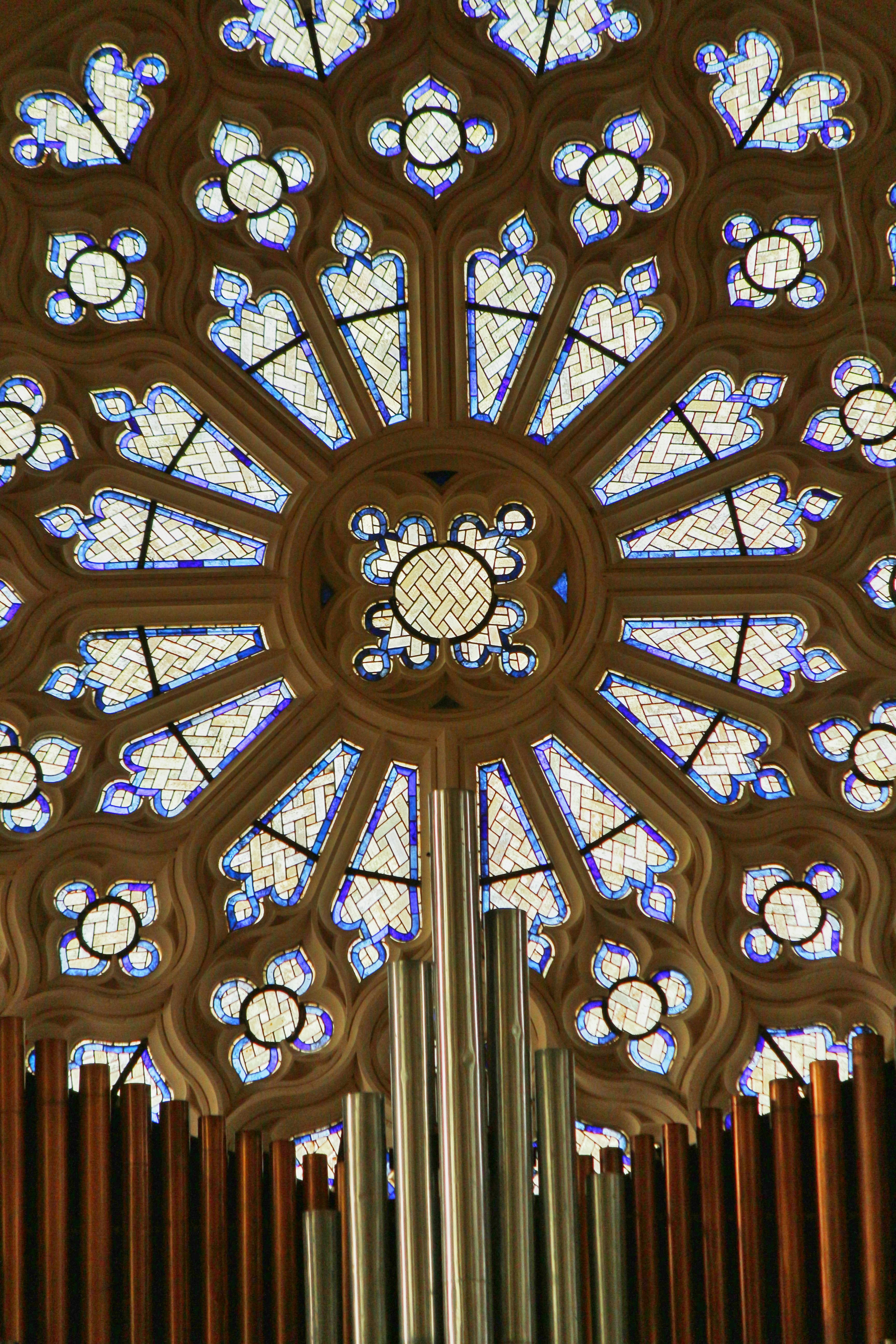 A detailed stained glass window with pipes below.