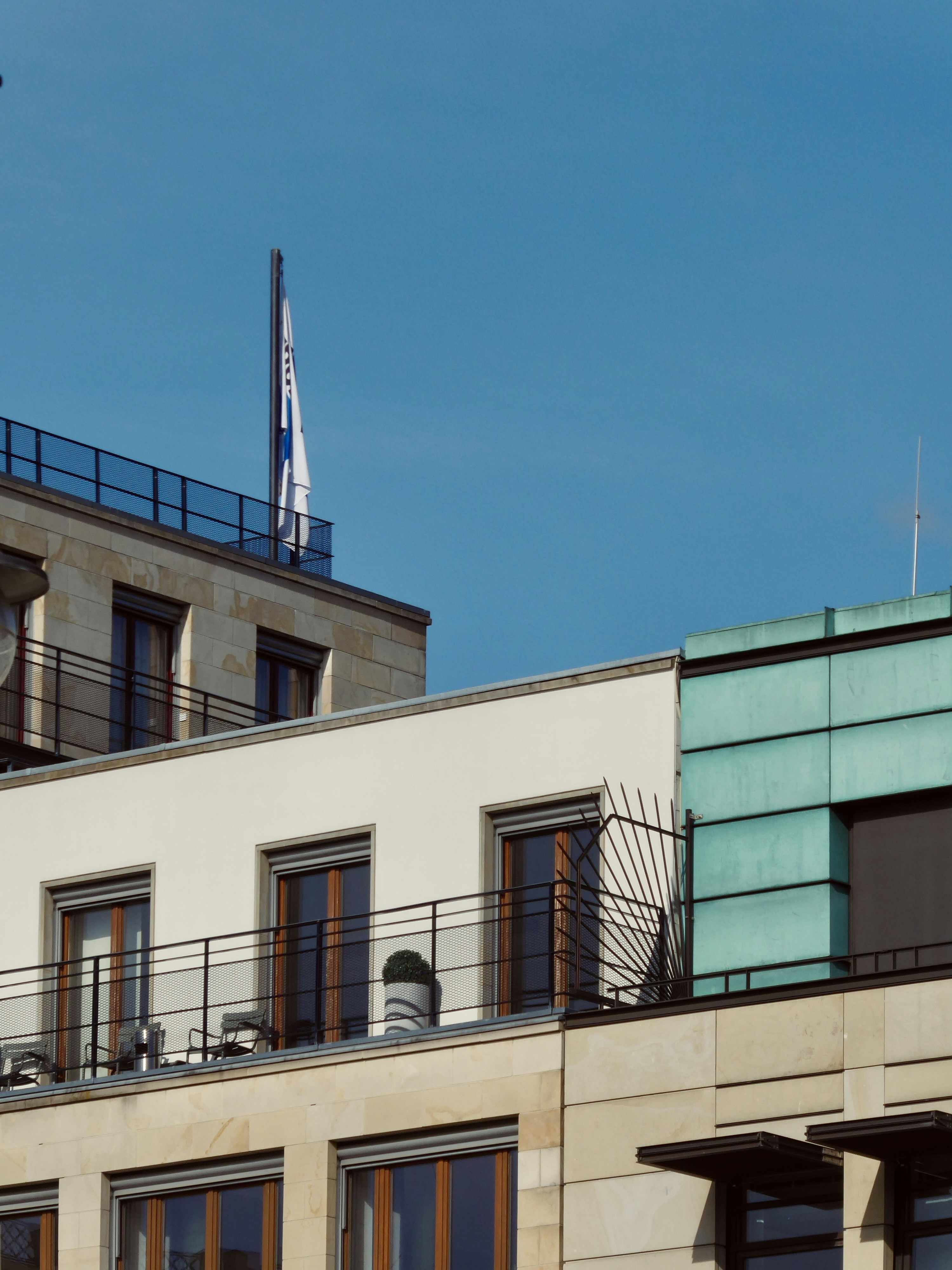 Buildings with flag against a bright blue sky.