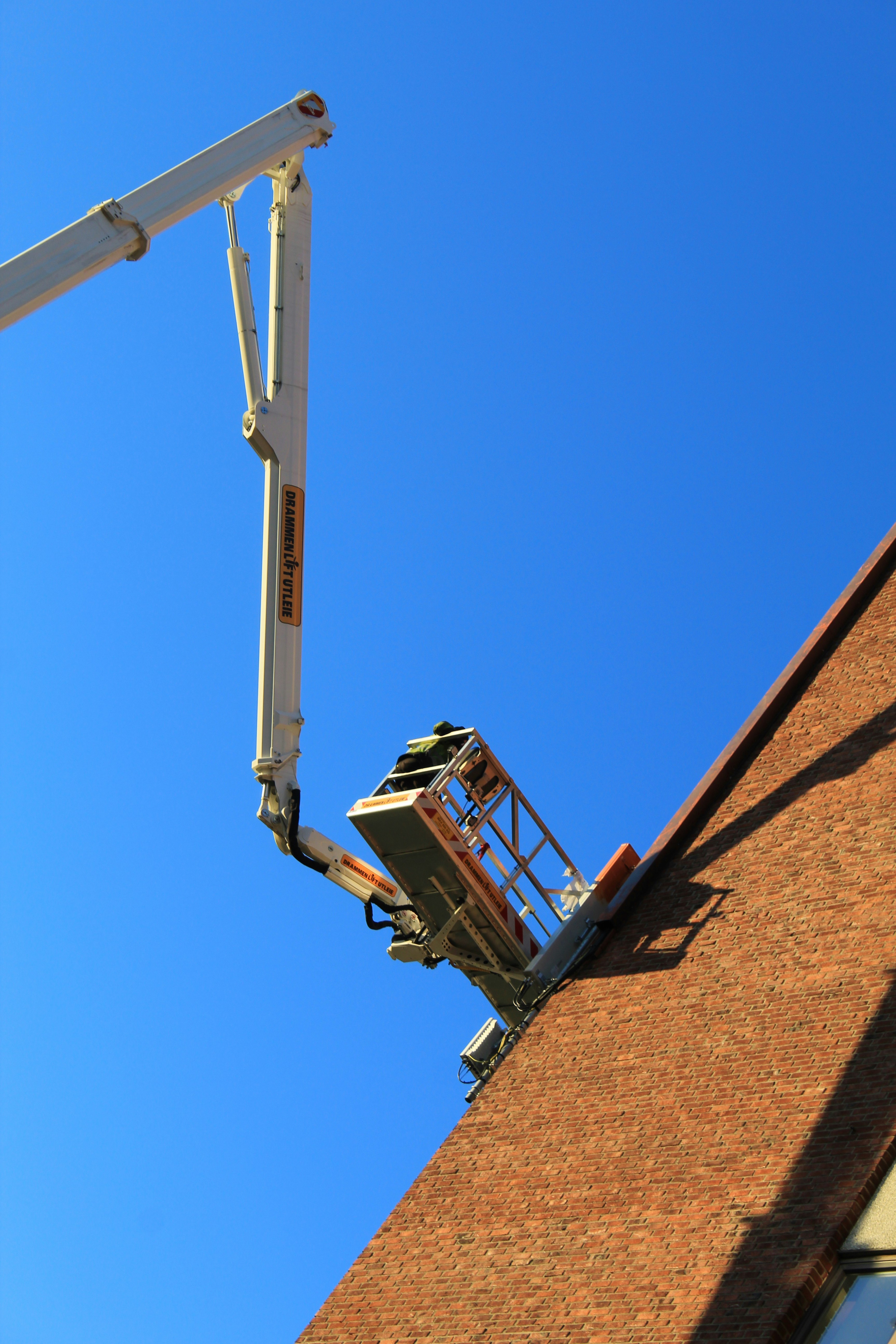 Arbejder i lift reparerer kanten af en murstensbygning.