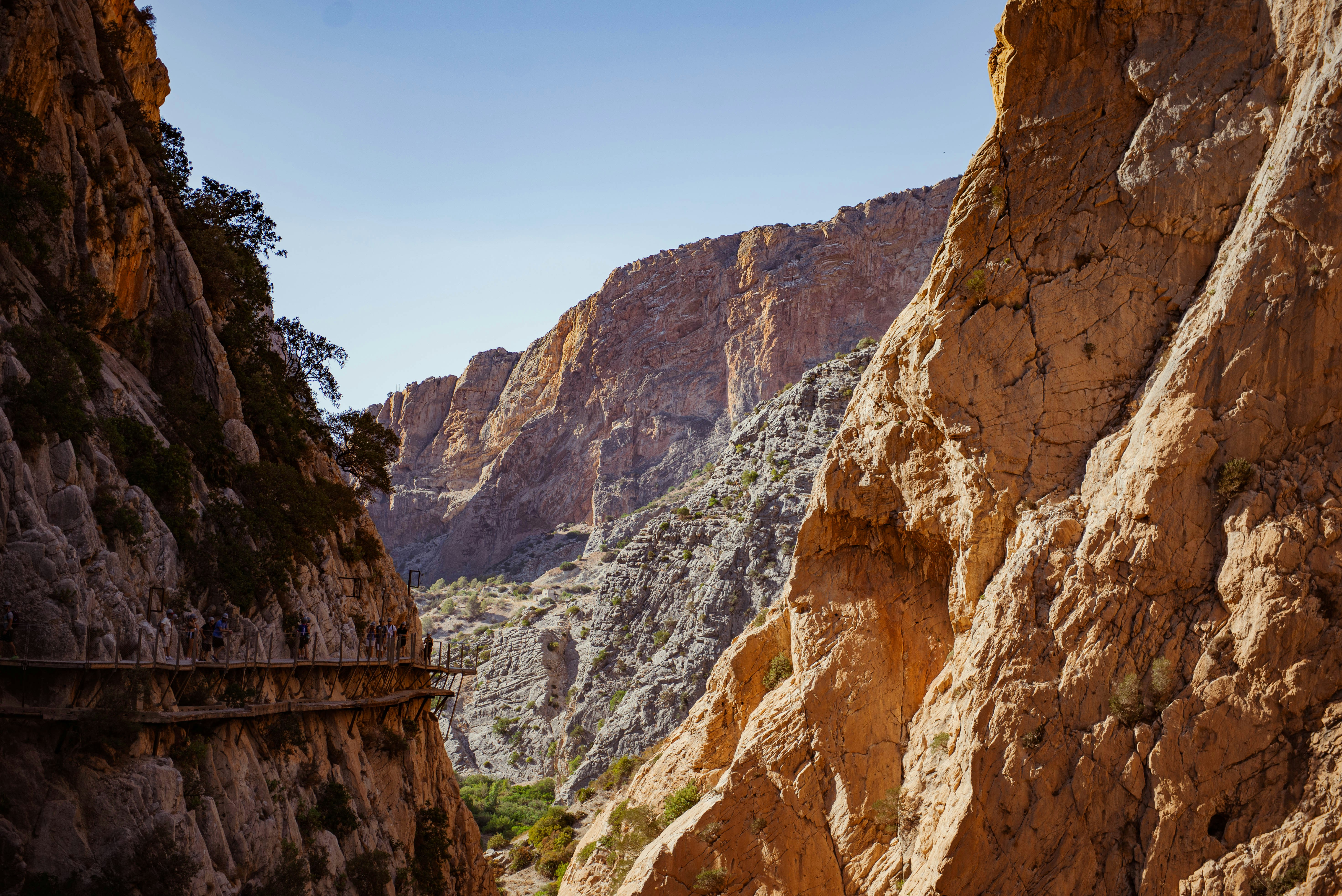 A canyon walkway leads through rocky mountains.