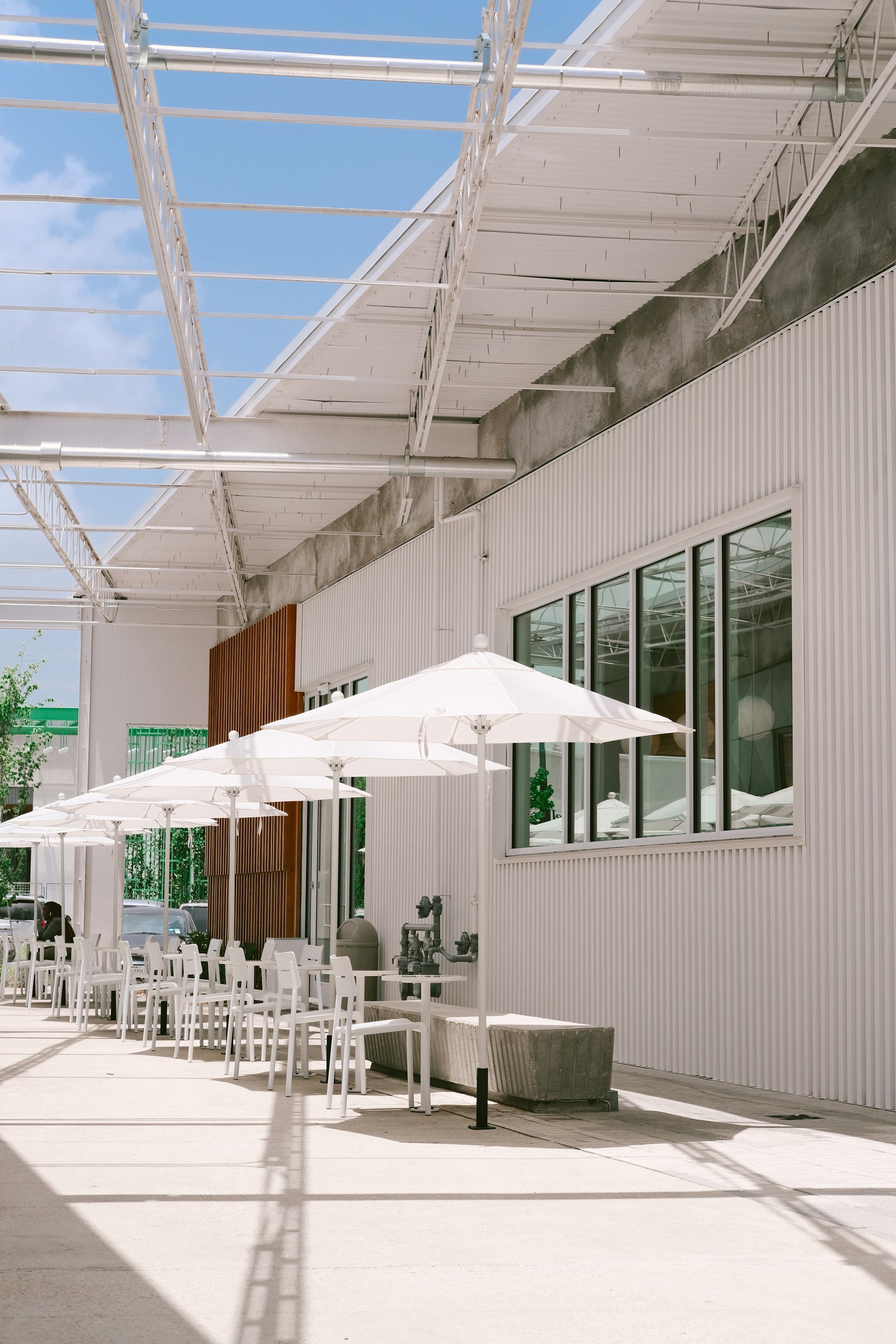 An outdoor cafe features white umbrellas and tables.