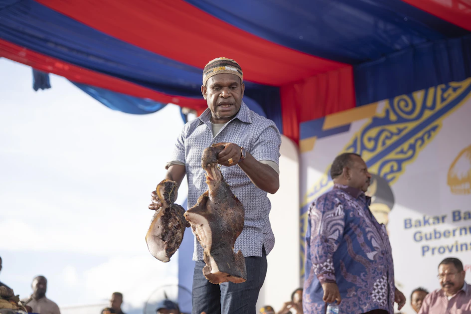 A man holds a carved object on stage.