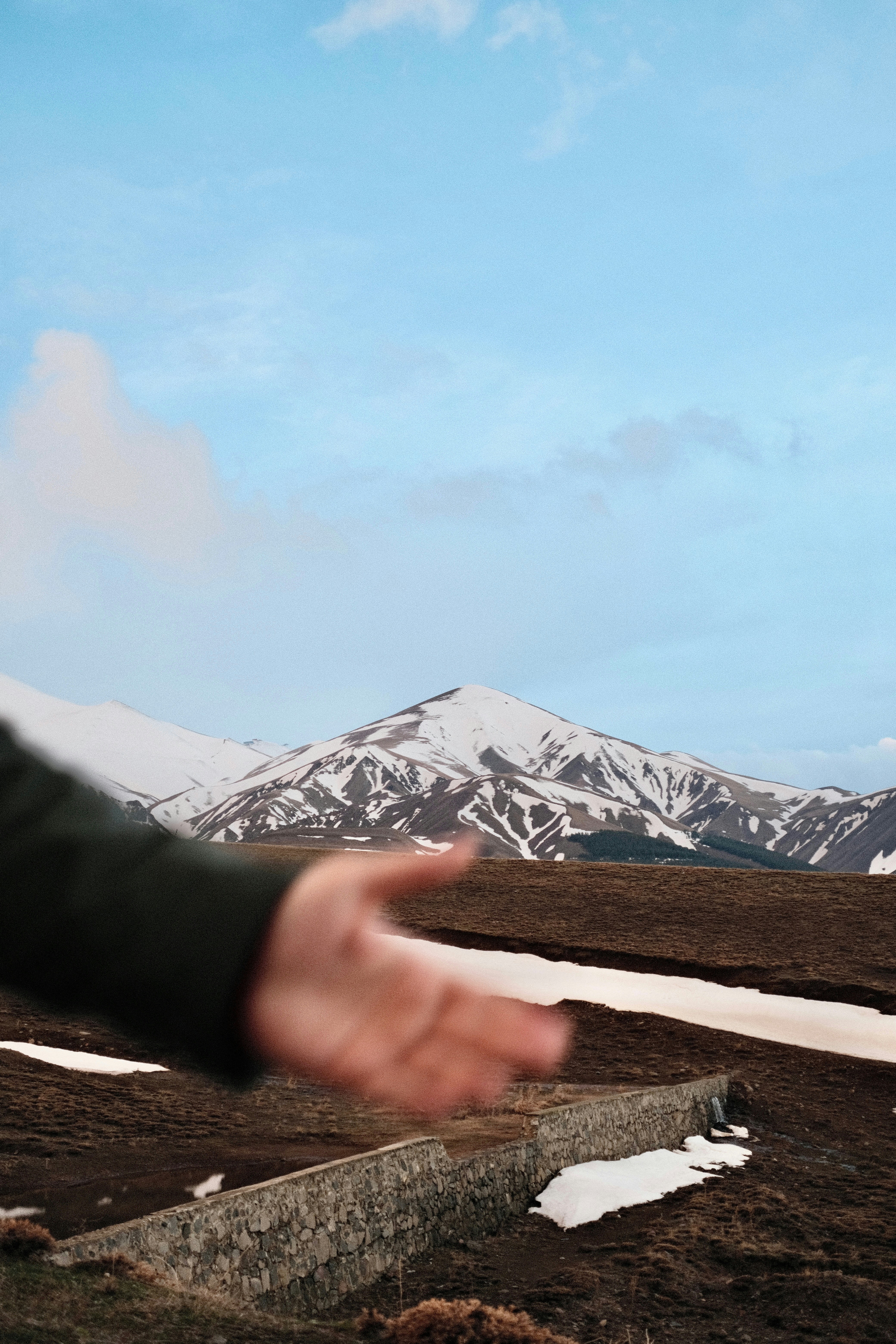 Uma mão se estende em direção às montanhas cobertas de neve.