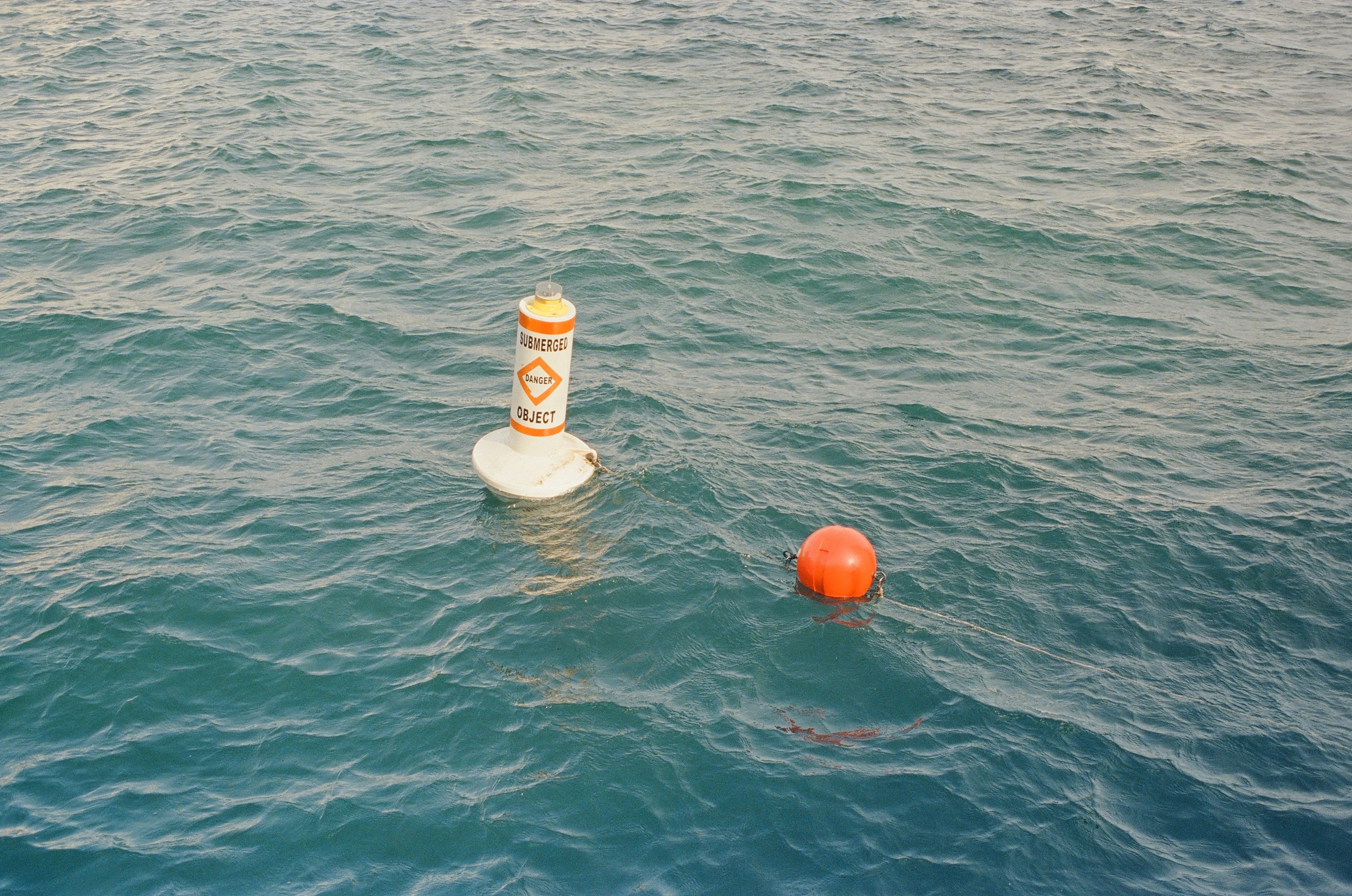 Buoys float in the ocean's calm, rippled waters.
