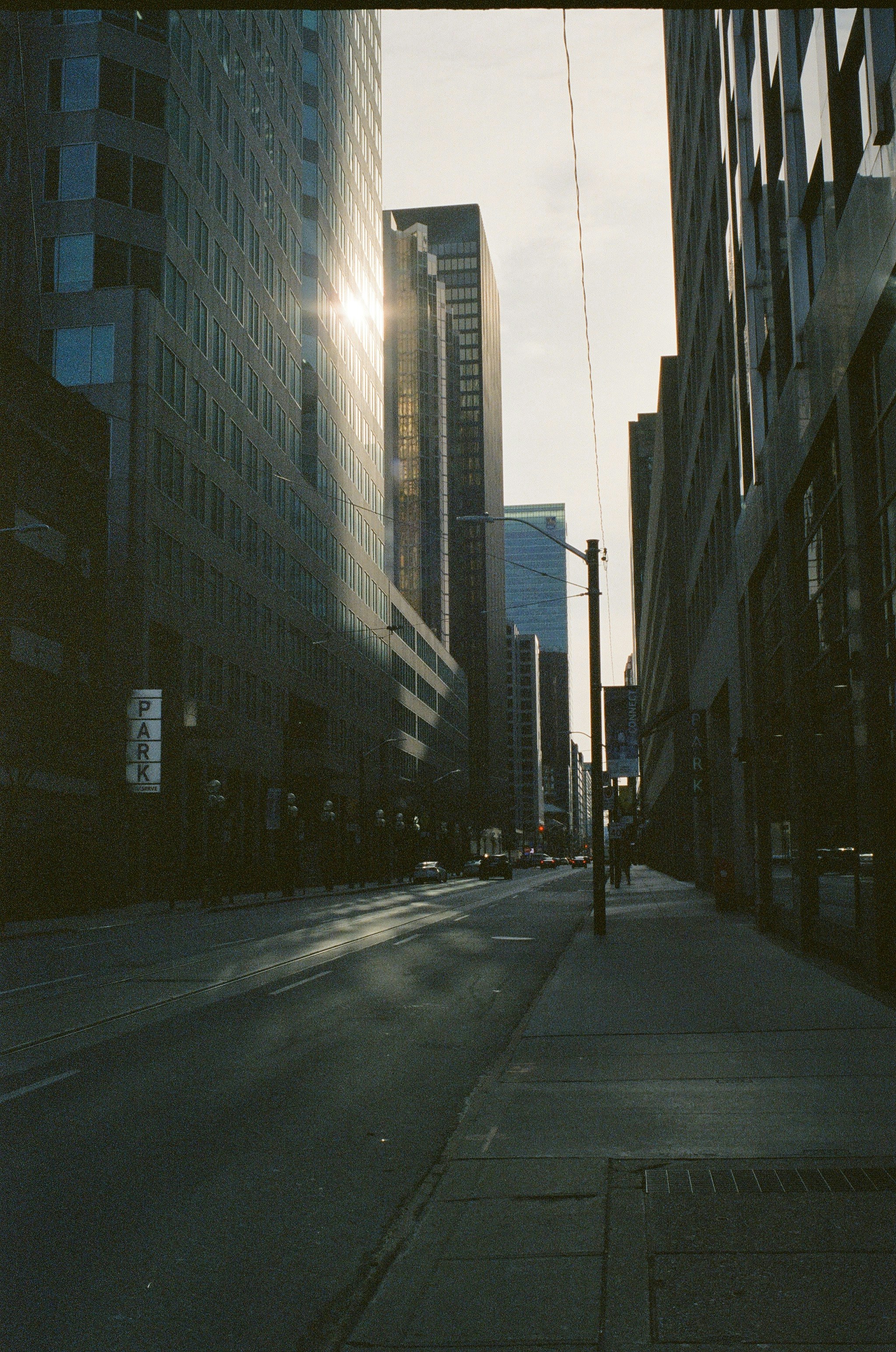 Buildings line a city street with bright sunlight.