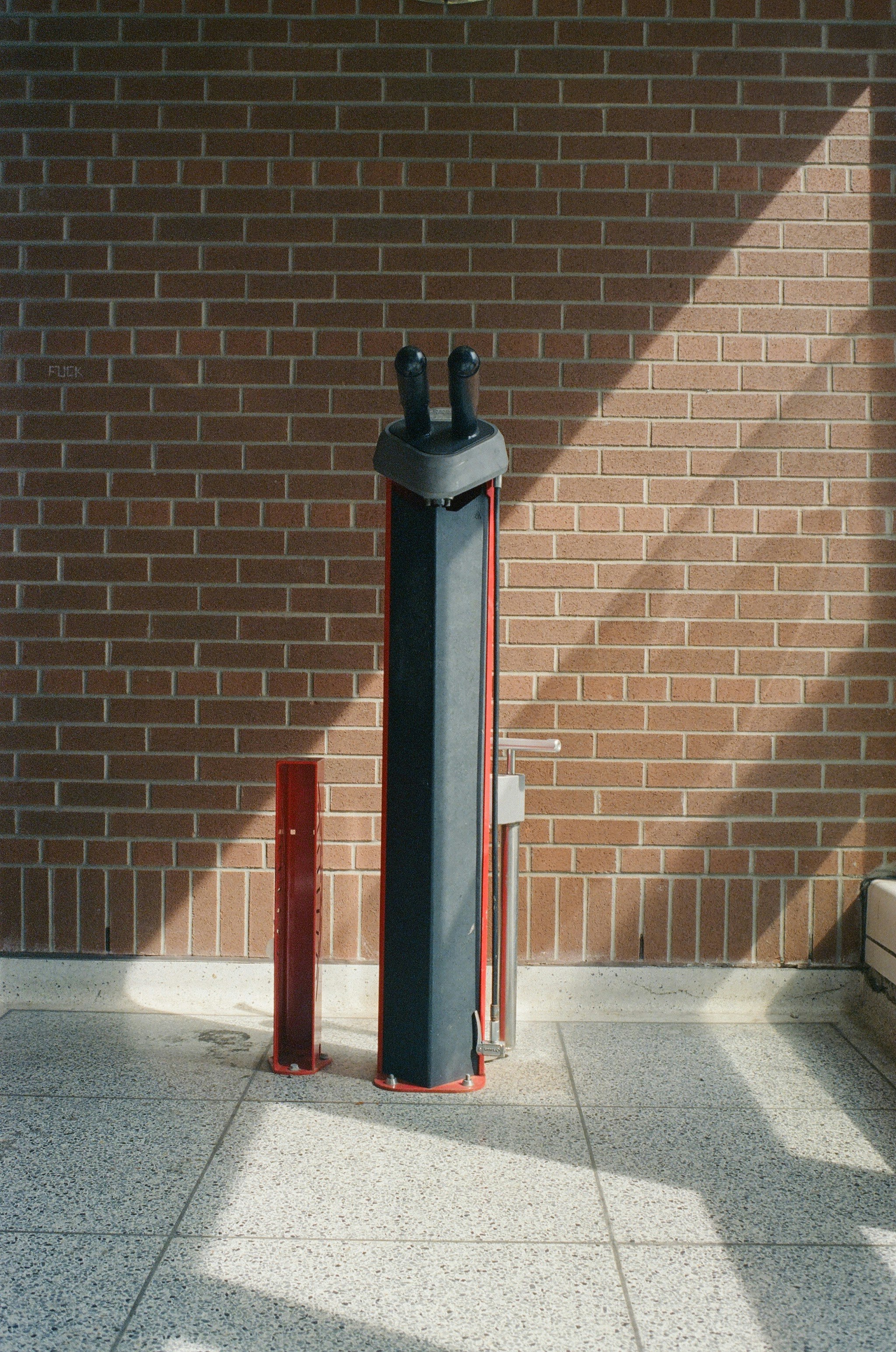 A bike pump station stands against a brick wall.