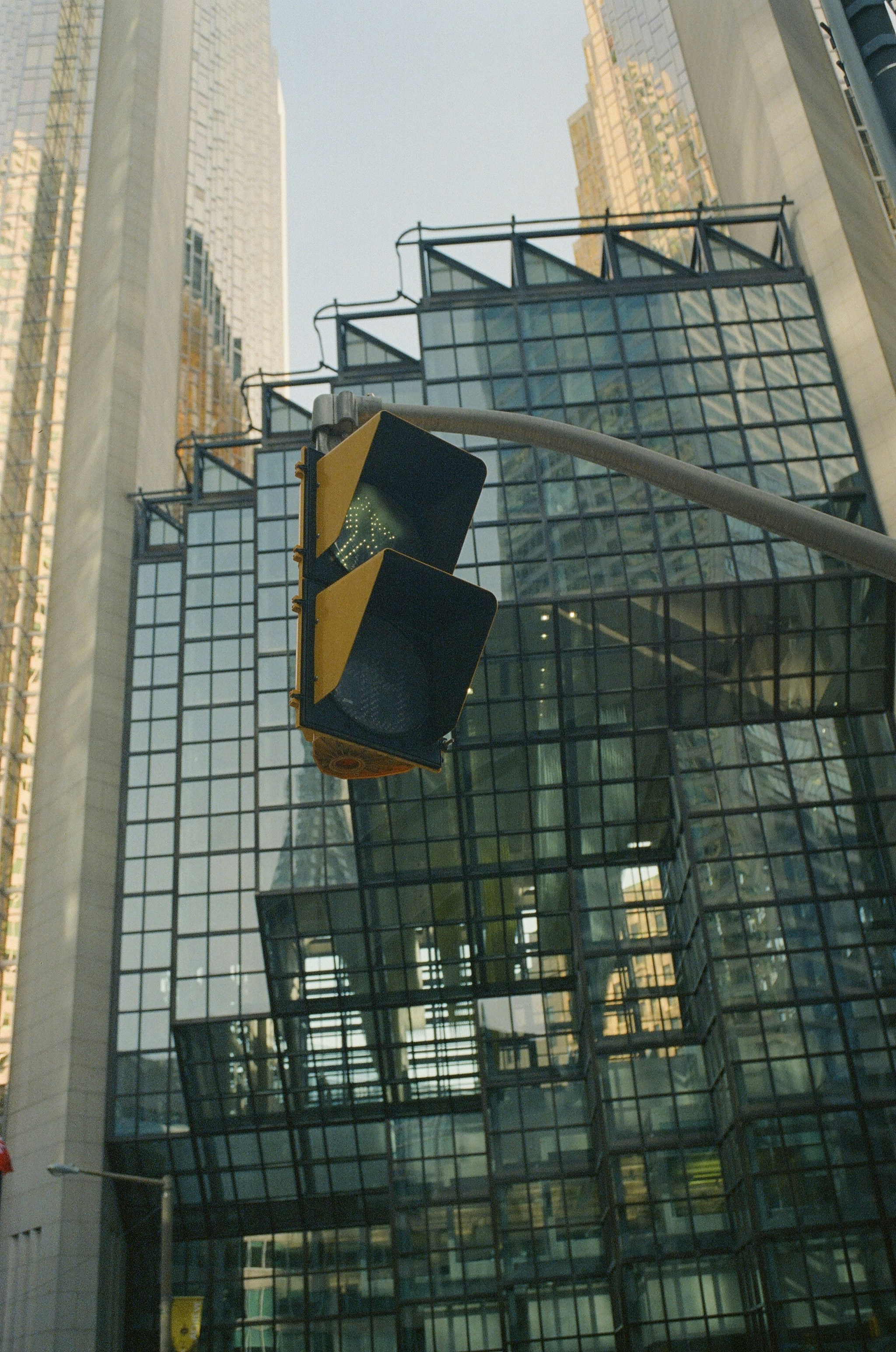 Traffic light hangs in front of modern, glassy buildings.