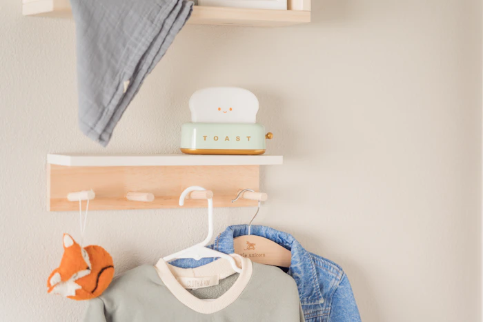 A cosy nursery shelf styled with baby clothes