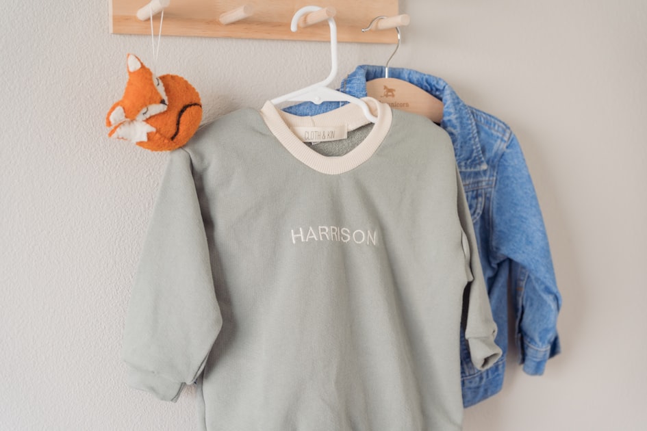 Clothes hang on a wooden rack against a wall.