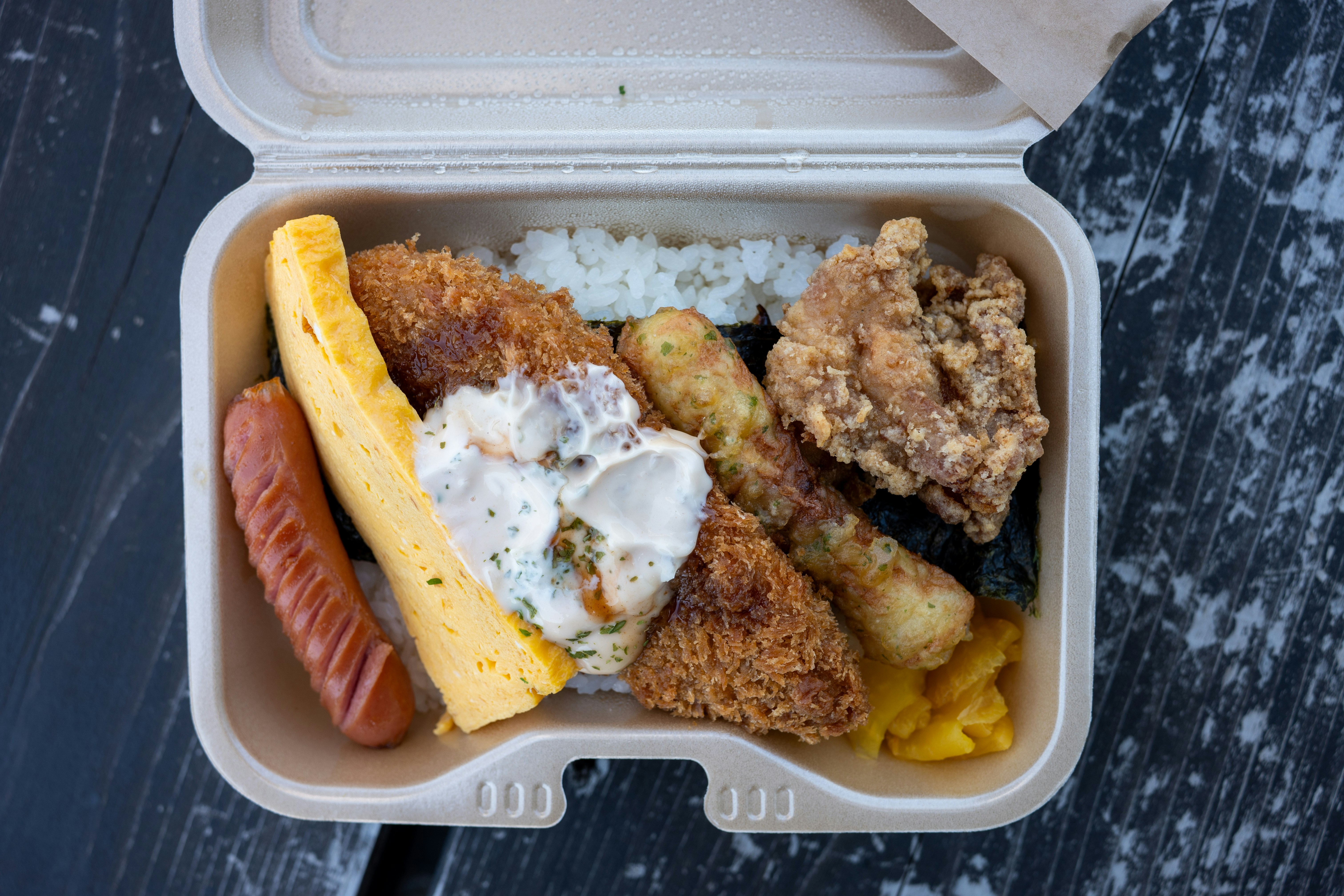 A bento box contains various japanese cuisine.