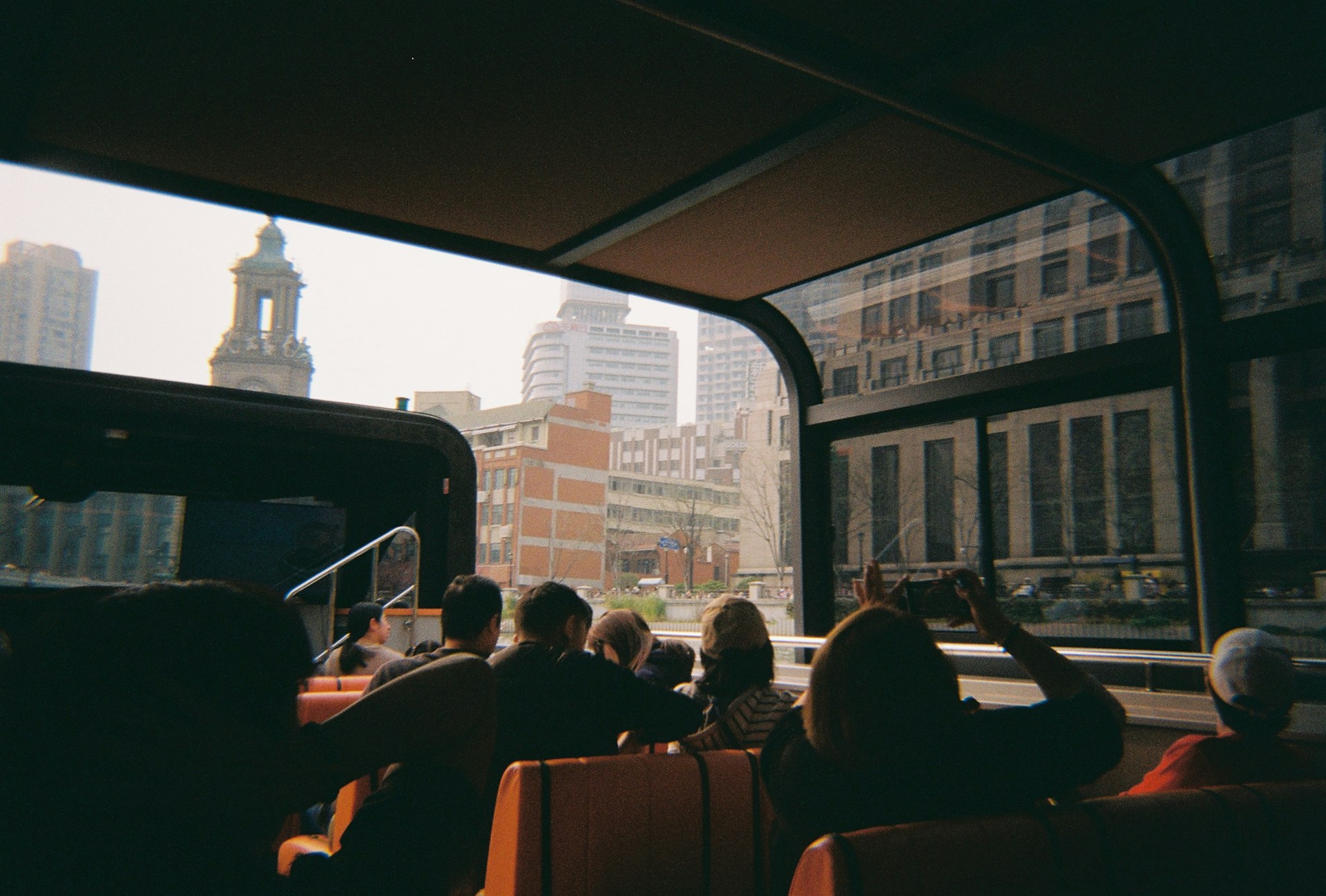 People ride a bus and view city buildings.