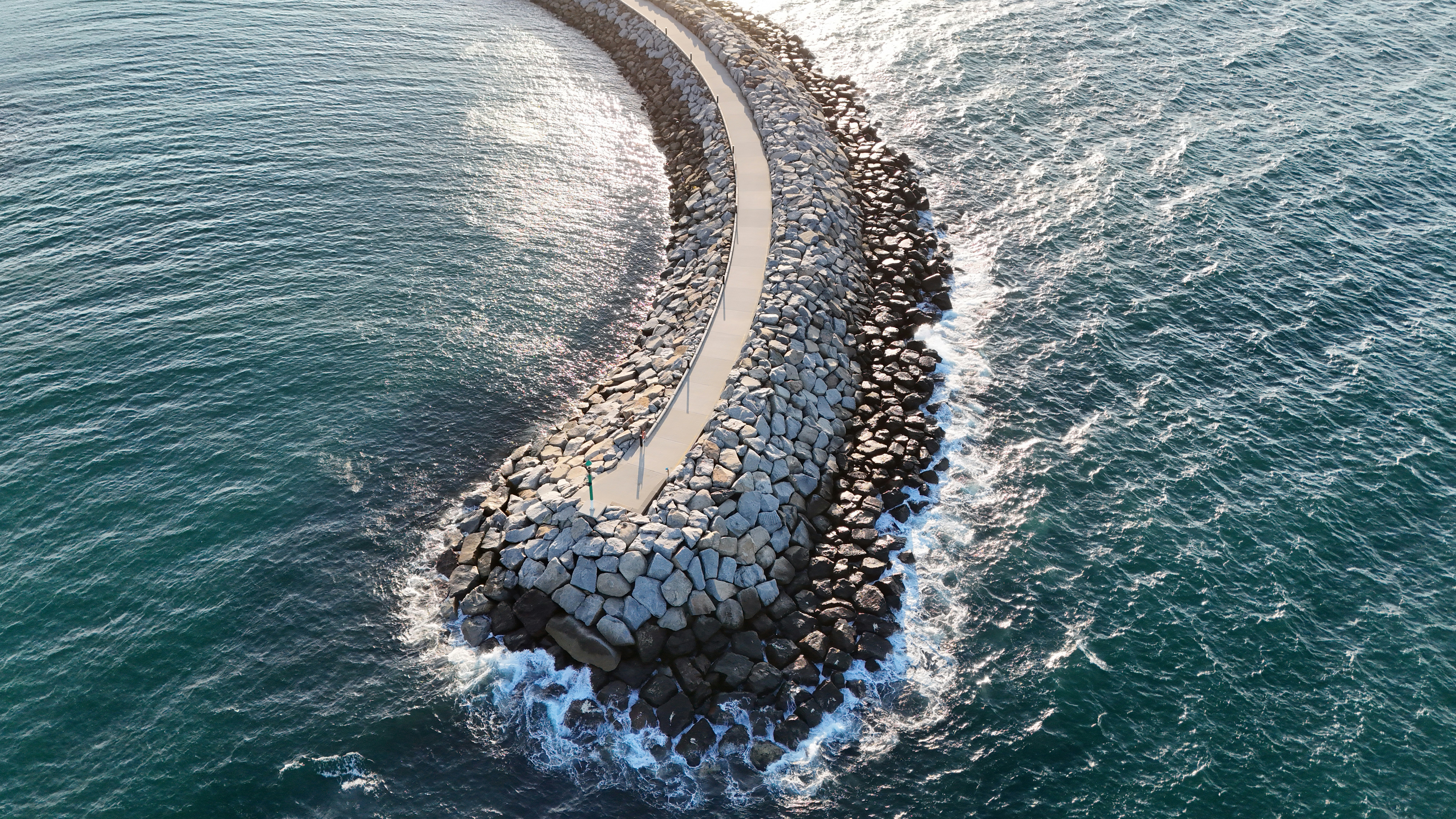 A stone pathway extends into the ocean.
