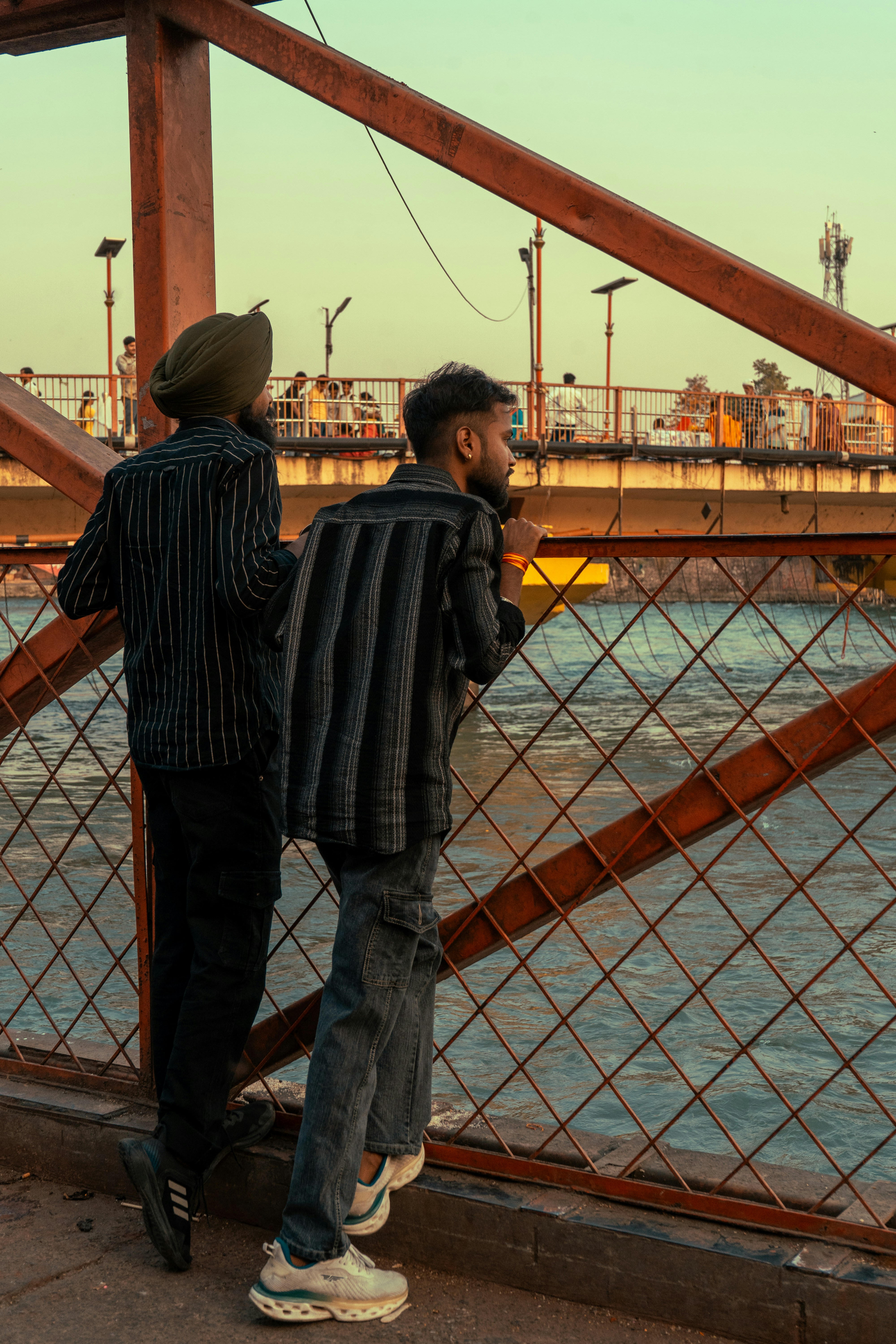 Two men look out over water from a bridge.