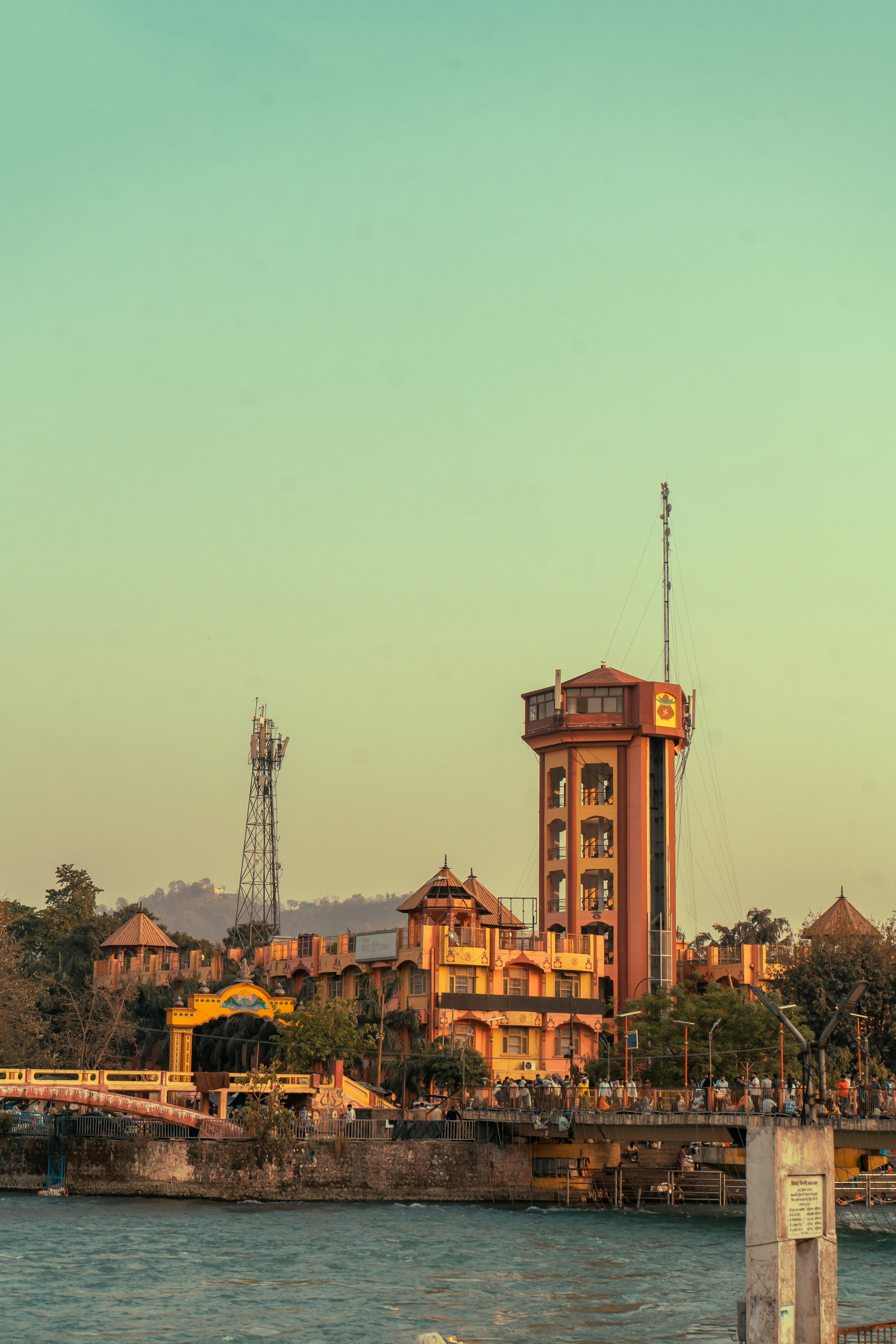 A building and antenna tower stand by a river.