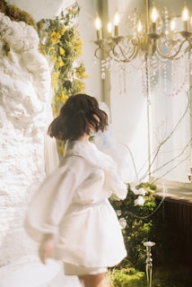 Woman in white dress twirls in an elegant room.