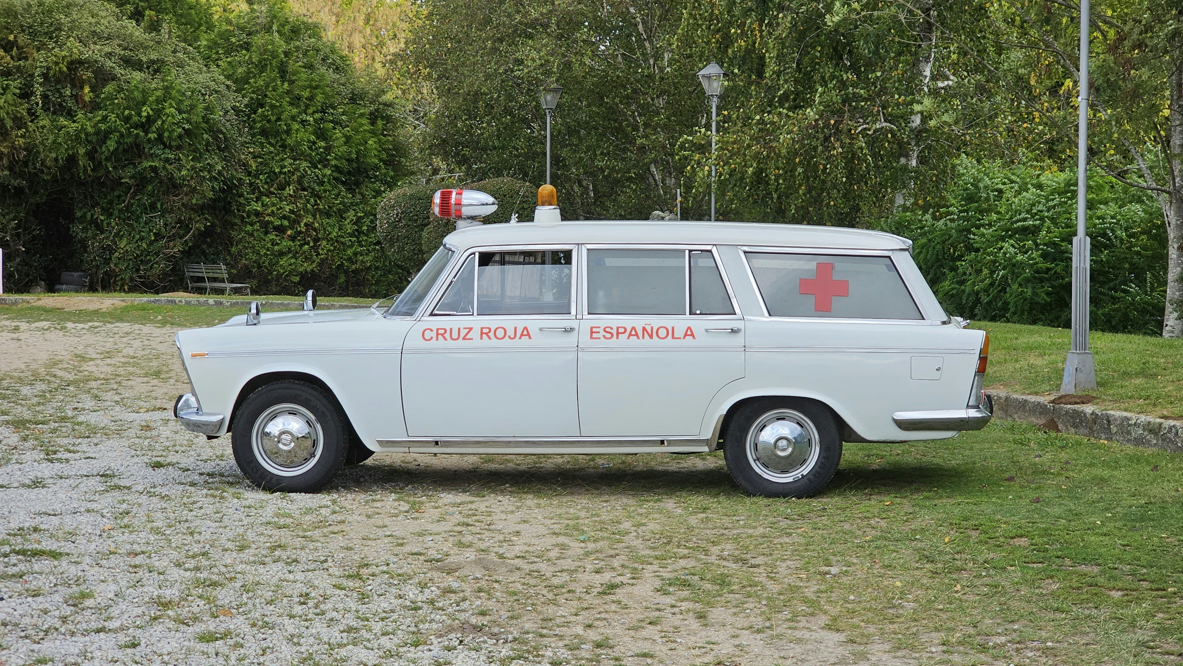 公園に白いヴィンテージの救急車が立っています。